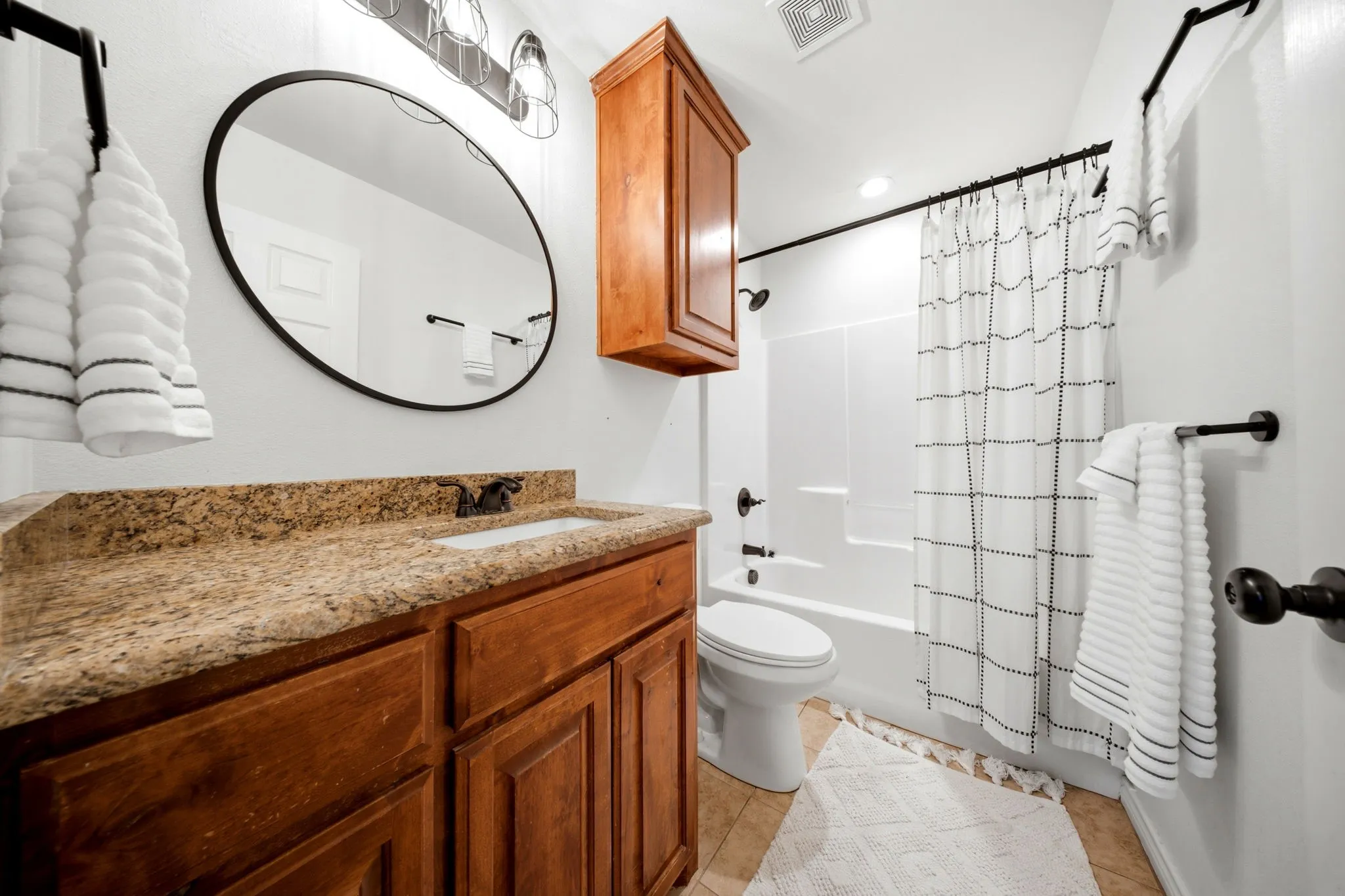 Primary bathroom features granite countertops, tile flooring, and a convenient tub-shower combination.