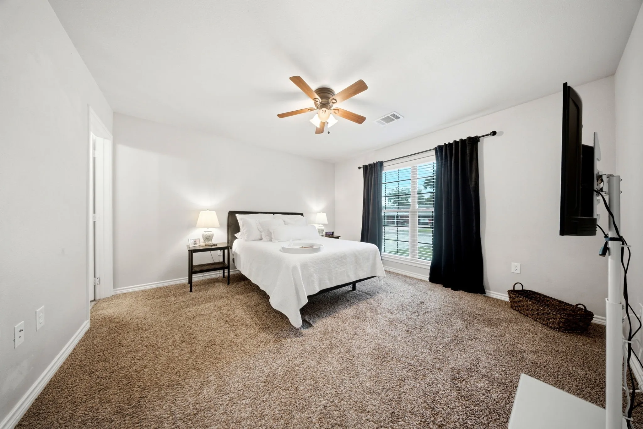 Spacious primary suite provides a private retreat with plush carpet and abundant natural light.
