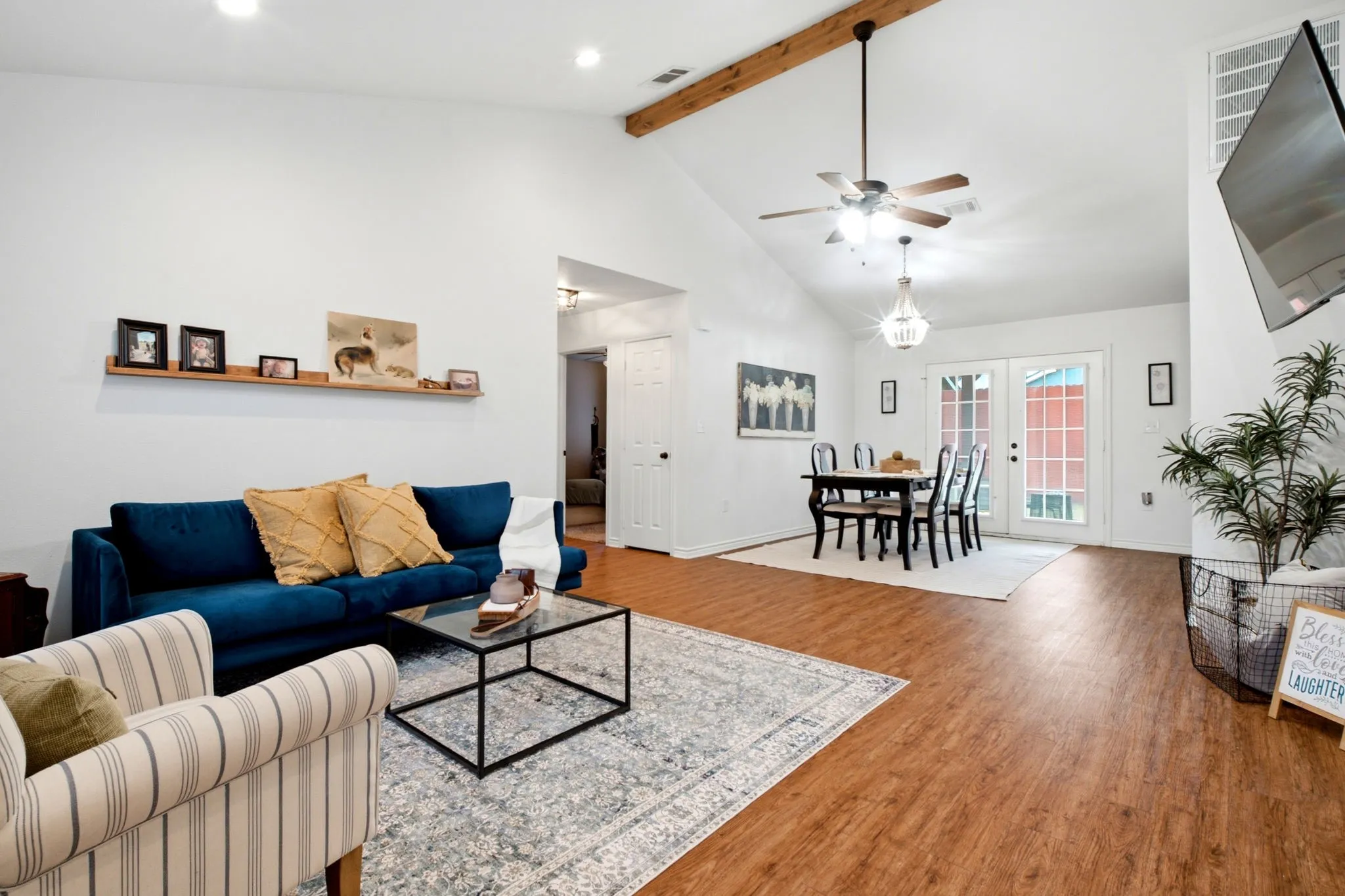 Open-concept living and dining area highlighted by vaulted ceilings, abundant natural light, and durable vinyl plank flooring.