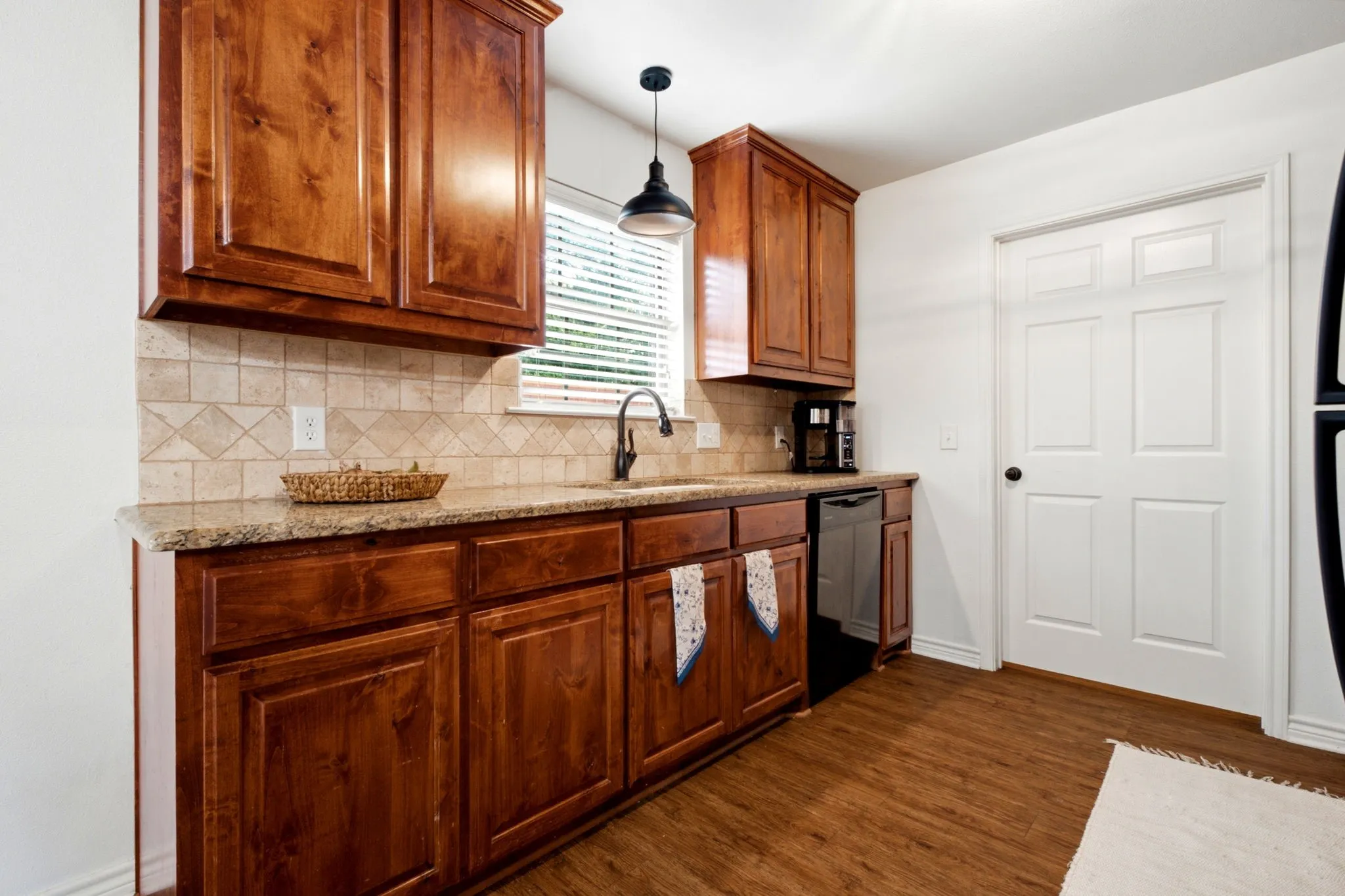 Well-appointed kitchen featuring granite countertops, real wood cabinetry, tile backsplash, and ample storage.