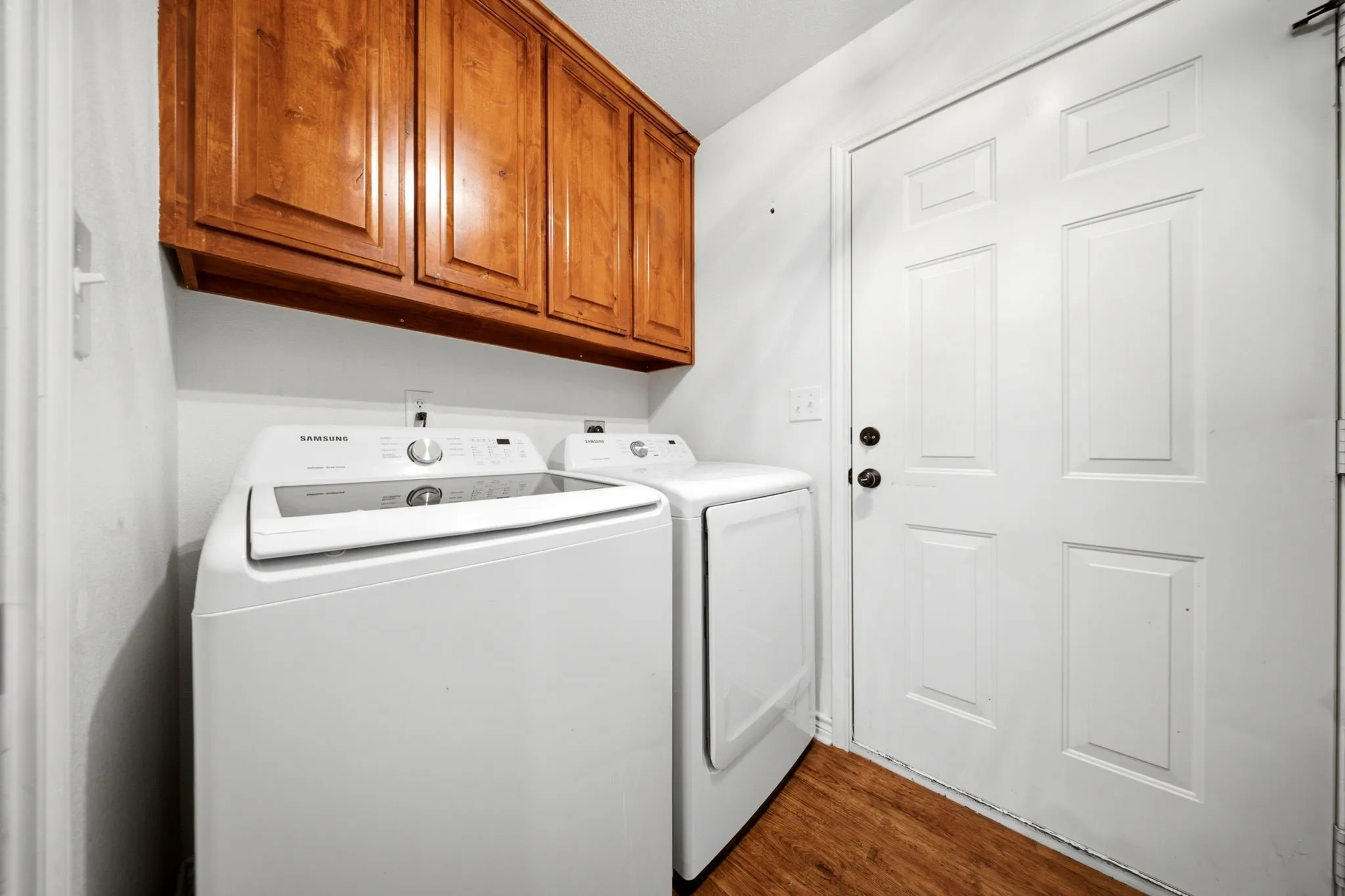Functional laundry room conveniently located between the kitchen and garage, complete with custom upper cabinetry for additional storage.