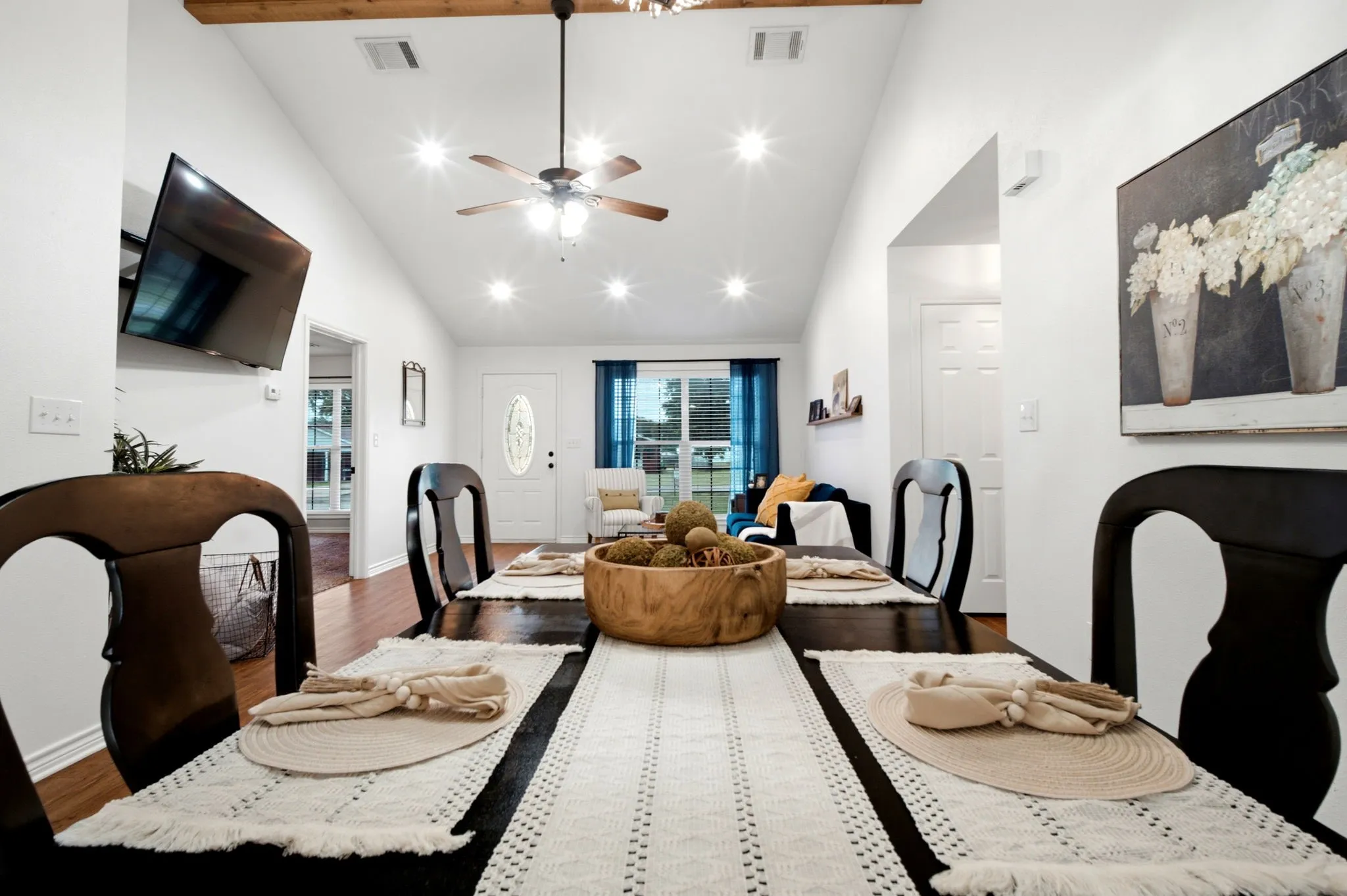 Dining area seamlessly connected to the living room, showcasing vaulted ceilings, wood beam accents, and an open-concept design ideal for entertaining.