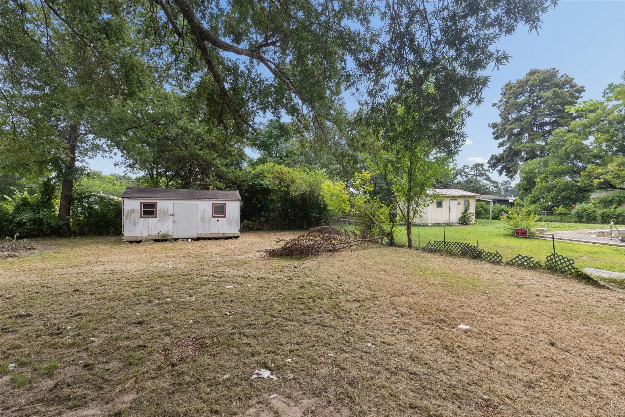 Expansive rear yard featuring a detached storage shed with double doors and two windows