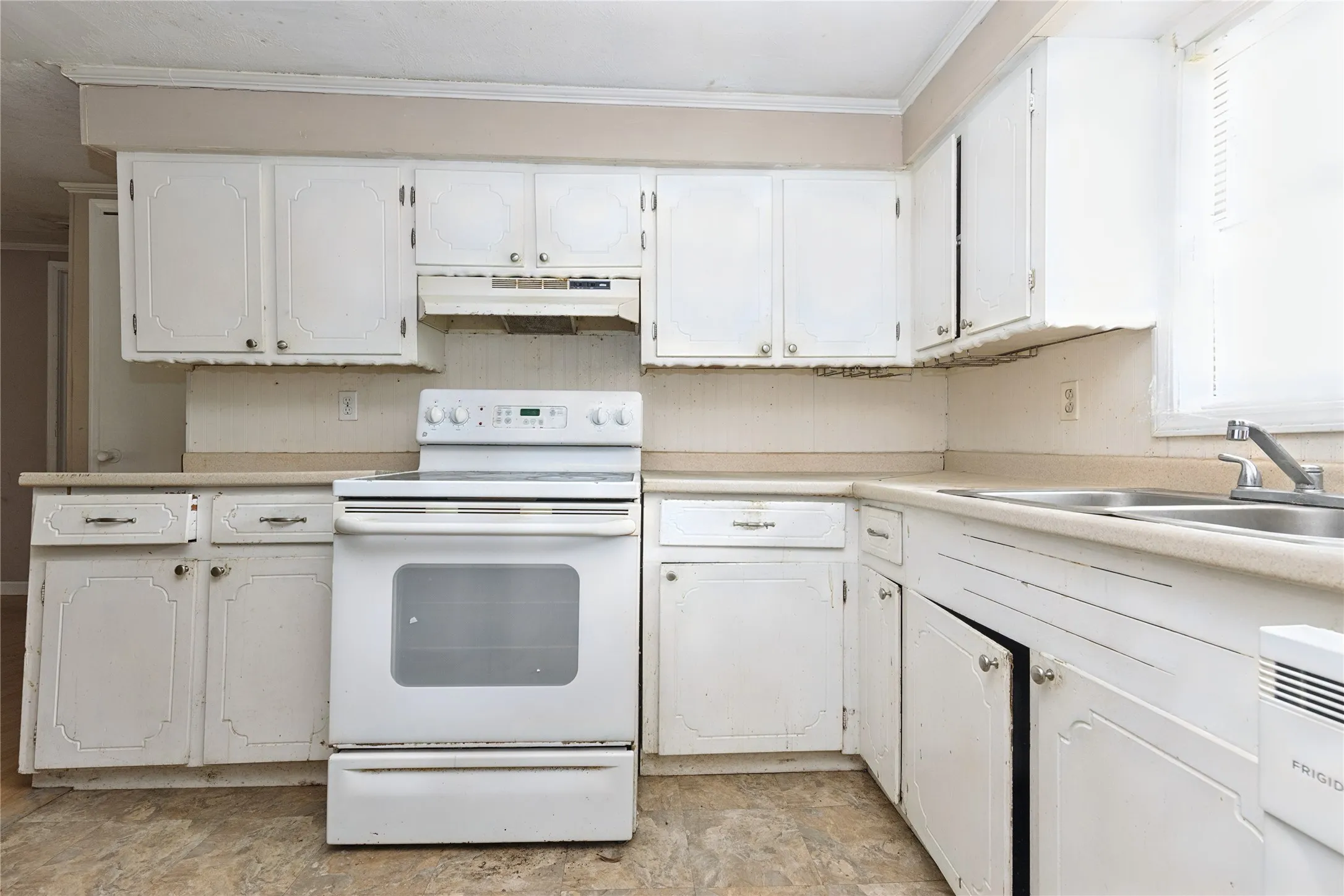 Kitchen featuring white cabinetry, a dual-basin sink, and a white electric range with an overhead vent