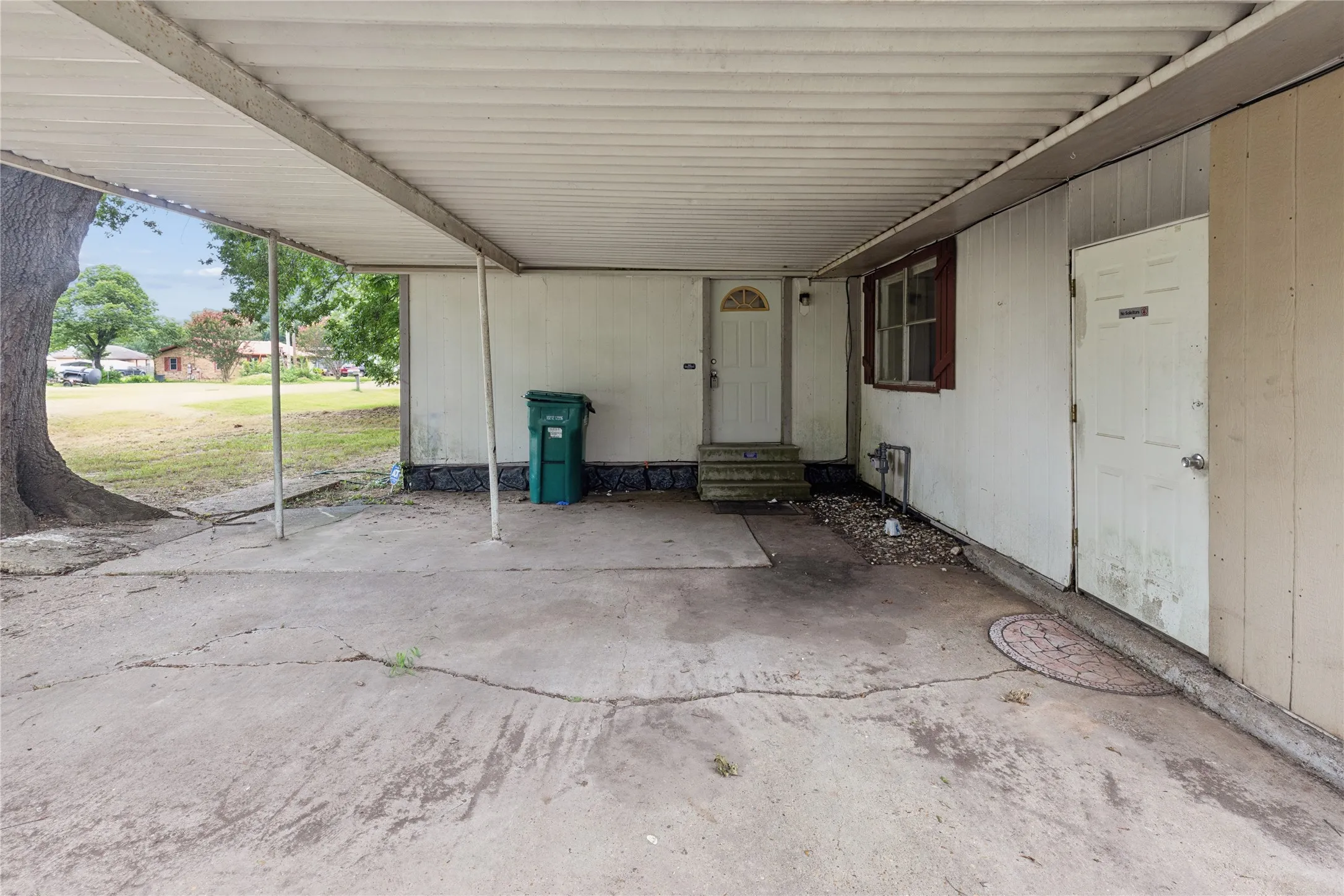 Carport featuring a concrete slab, metal roofing, and structural support posts