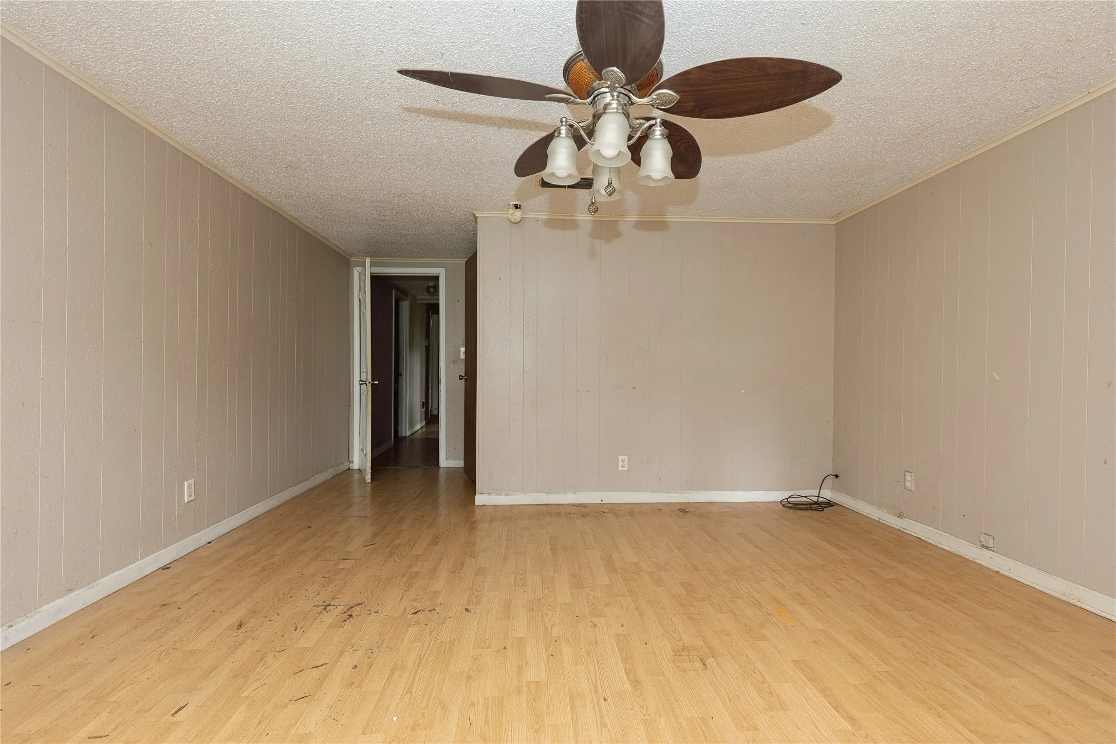 Spacious interior featuring wood-finish flooring, panel walls, and a ceiling fan with integrated lighting