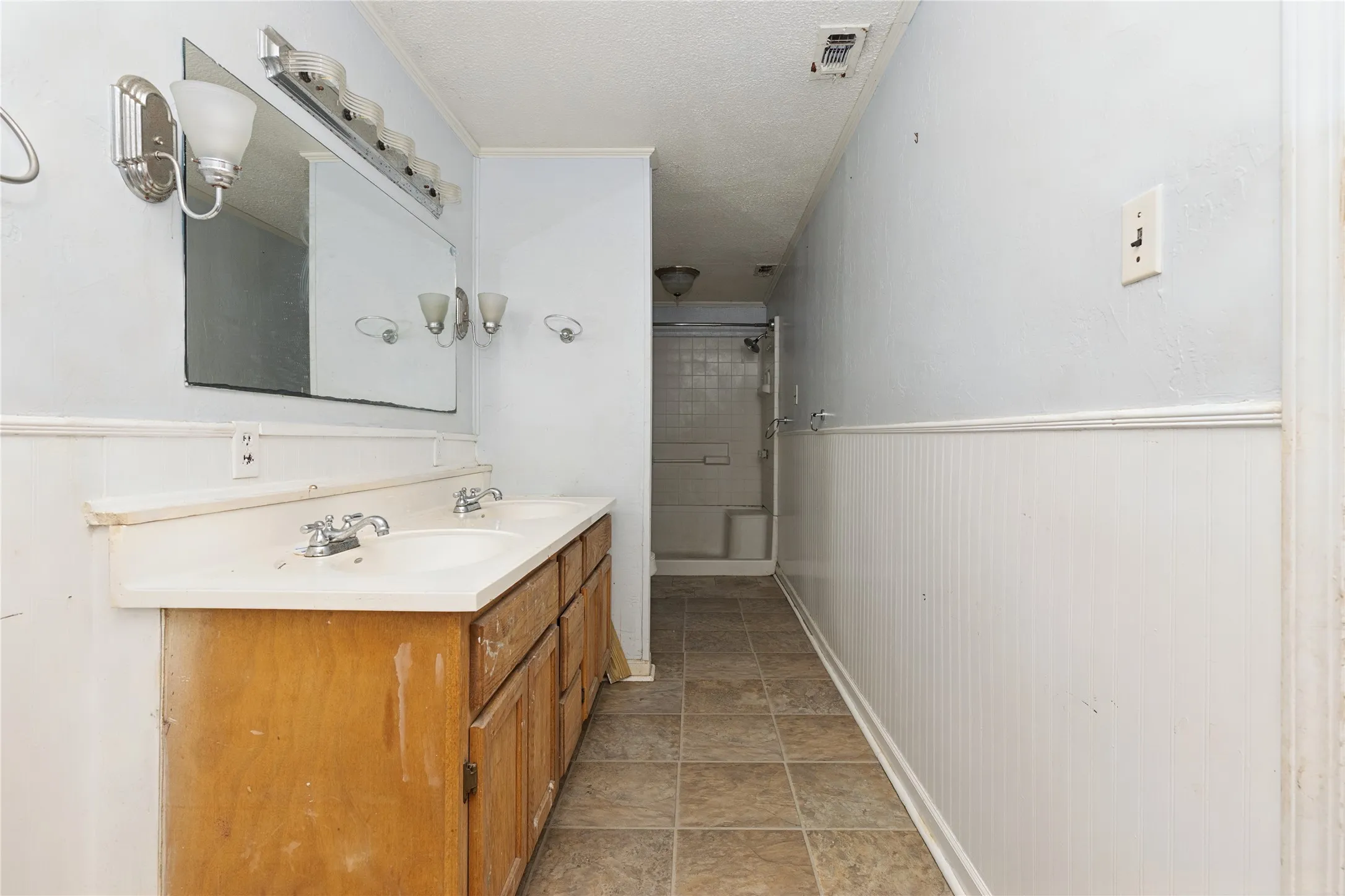 Bathroom with dual vanity, wall-mounted mirror, and overhead lighting fixture