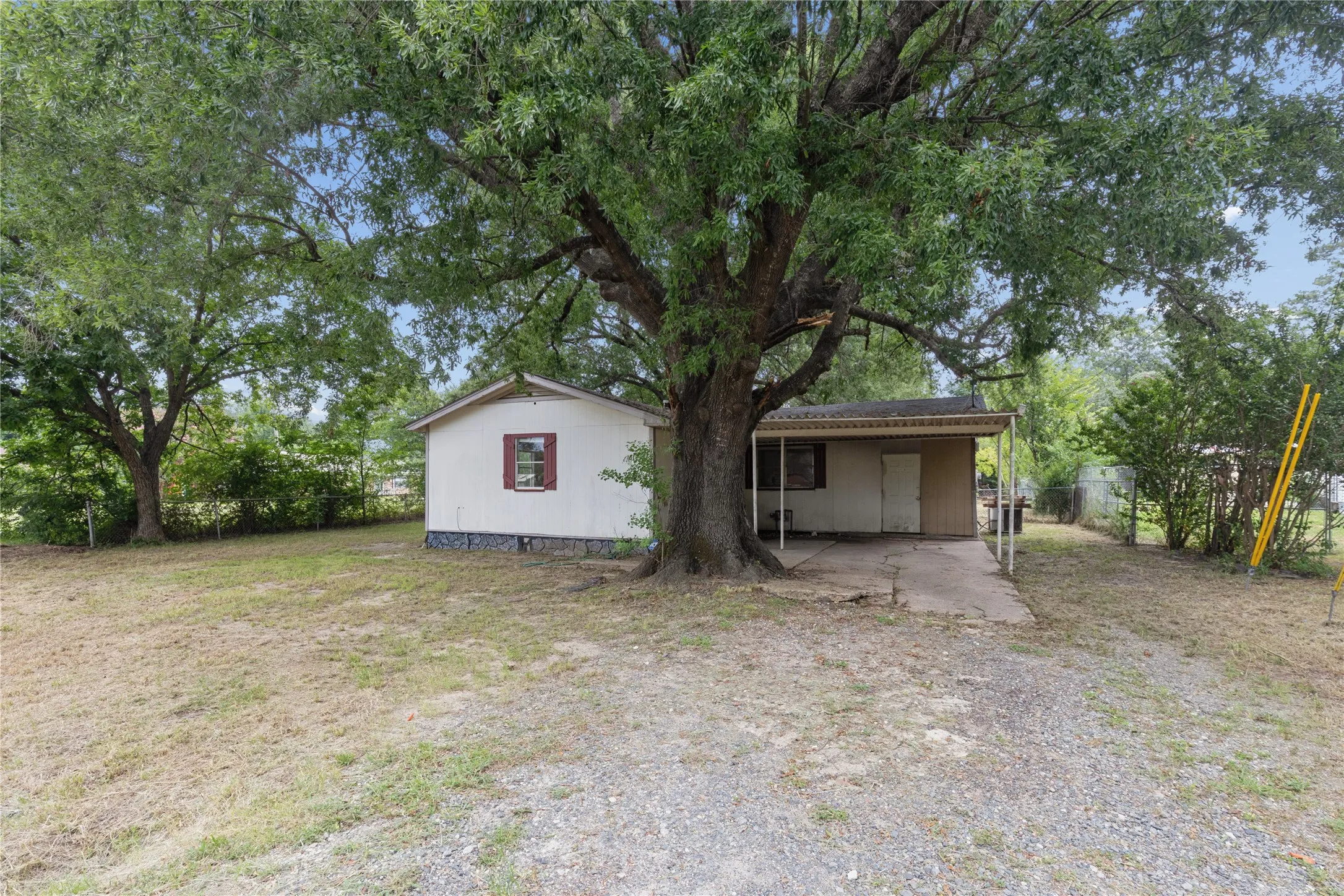 Single-story residence featuring a covered entry, an attached carport, and a gravel driveway