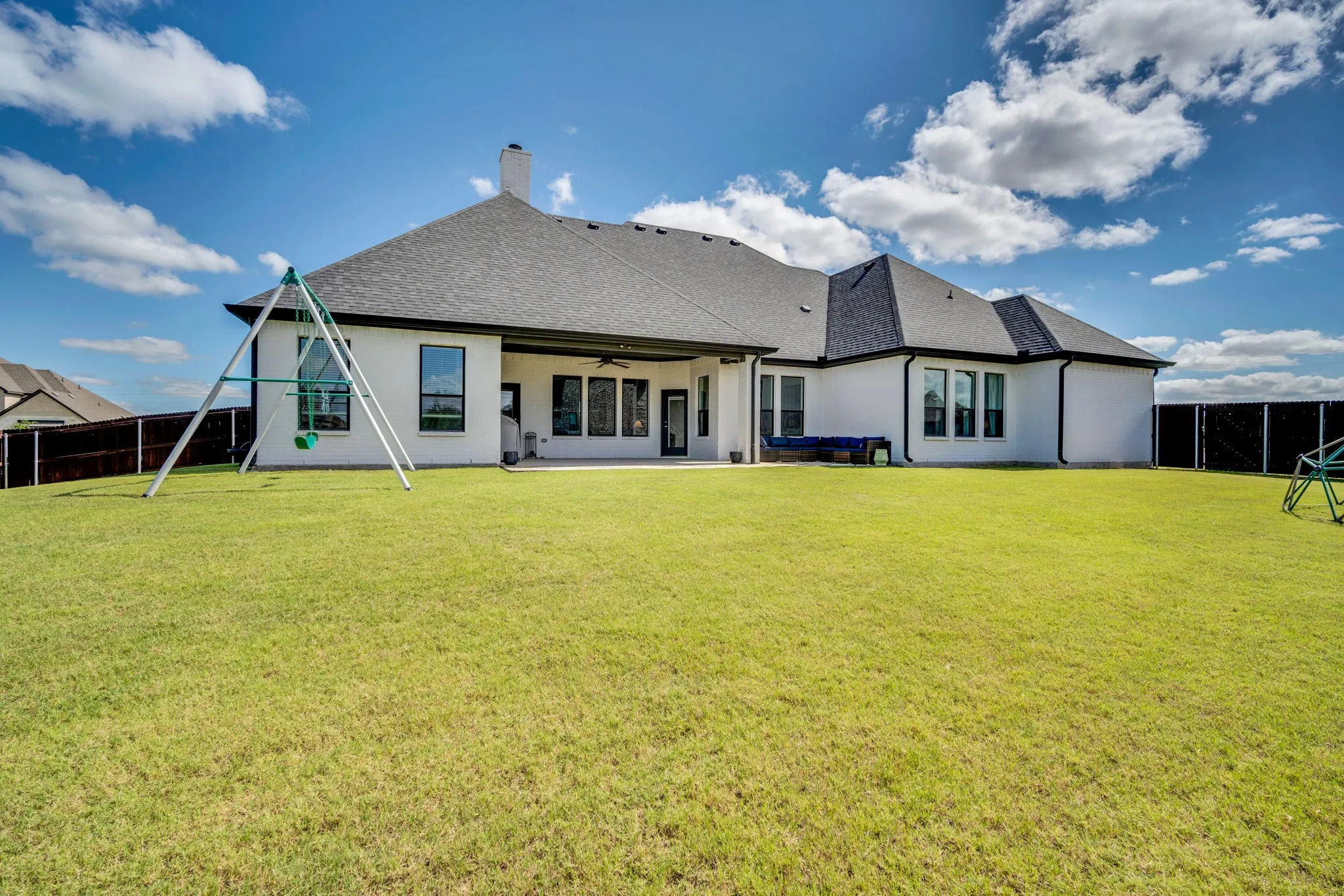Expansive green lawn with a white stucco exterior and dark-framed windows