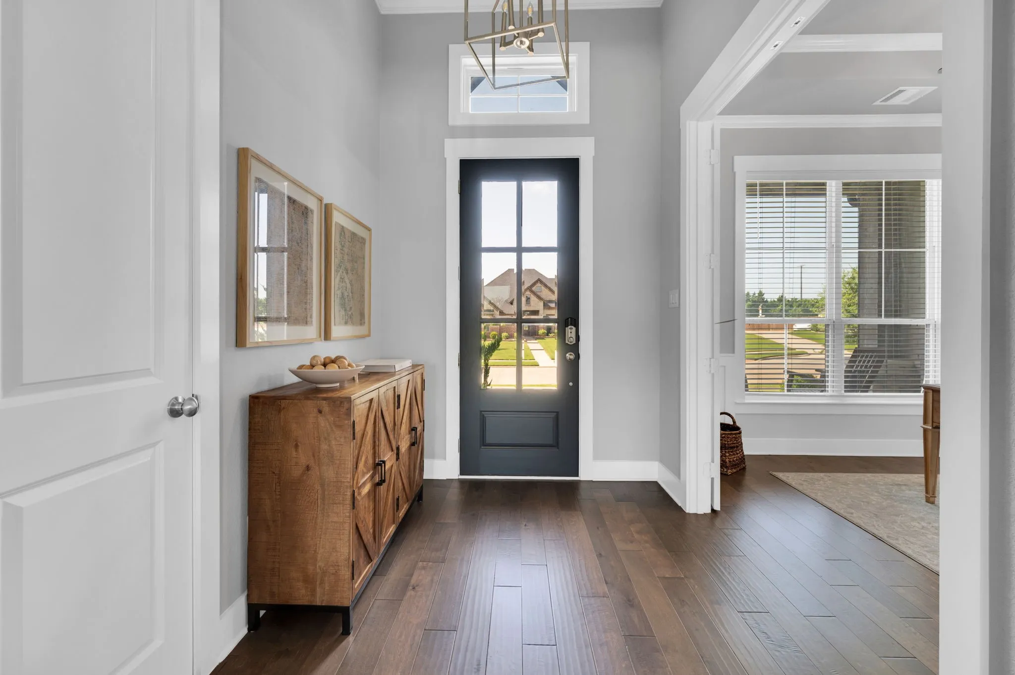 Entryway featuring a dark paneled door with glass inserts, transom window, and a geometric chandelier