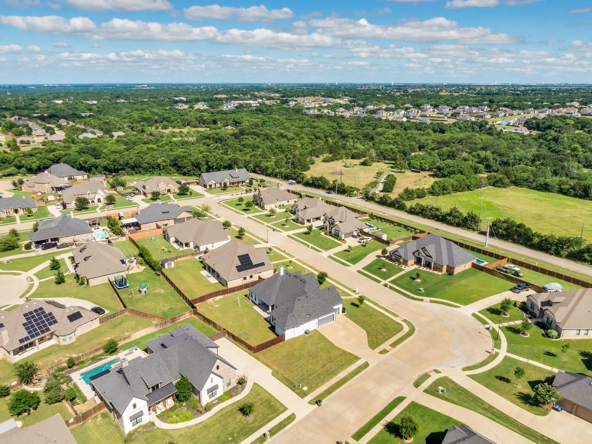Residential neighborhood featuring a mix of single-family homes, some with private swimming pools and solar panels