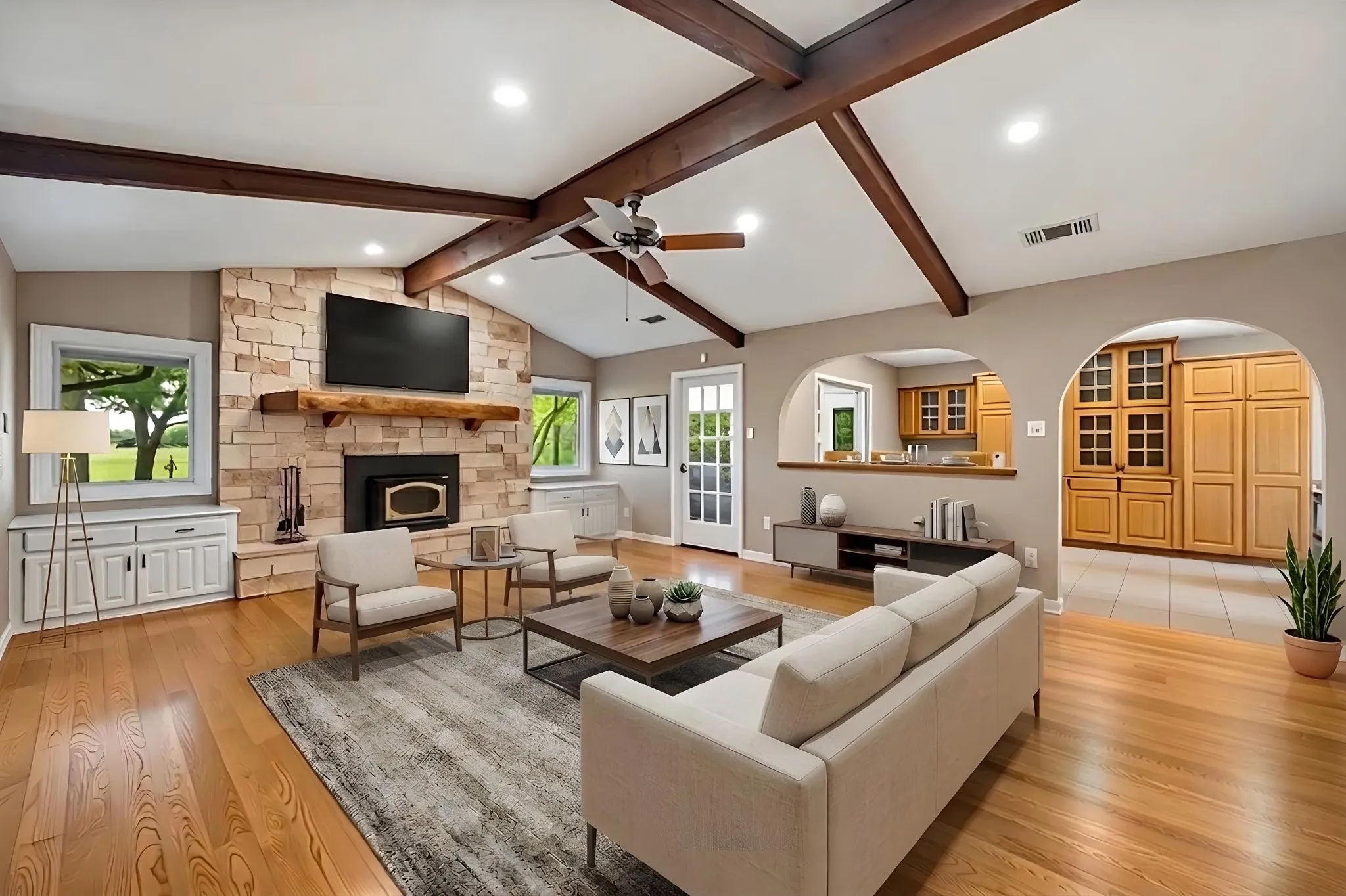 virtually staged living room with wood burning fireplace and vaulted ceilings with exposed wood beams