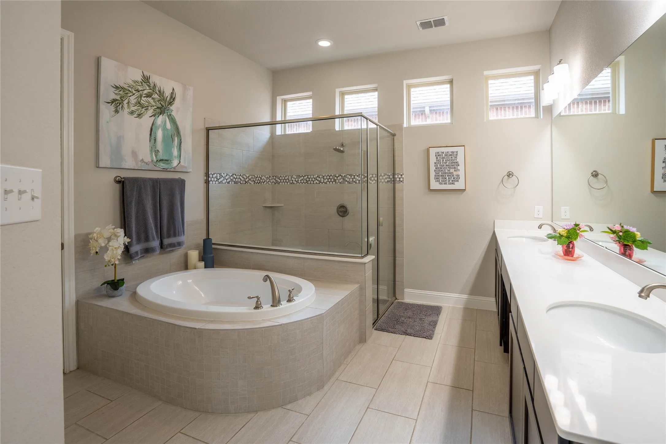 Built-in soaking tub with brushed nickel fixtures, glass-enclosed shower with tiled surround, and a dual vanity featuring undermount sinks and extensive counter space