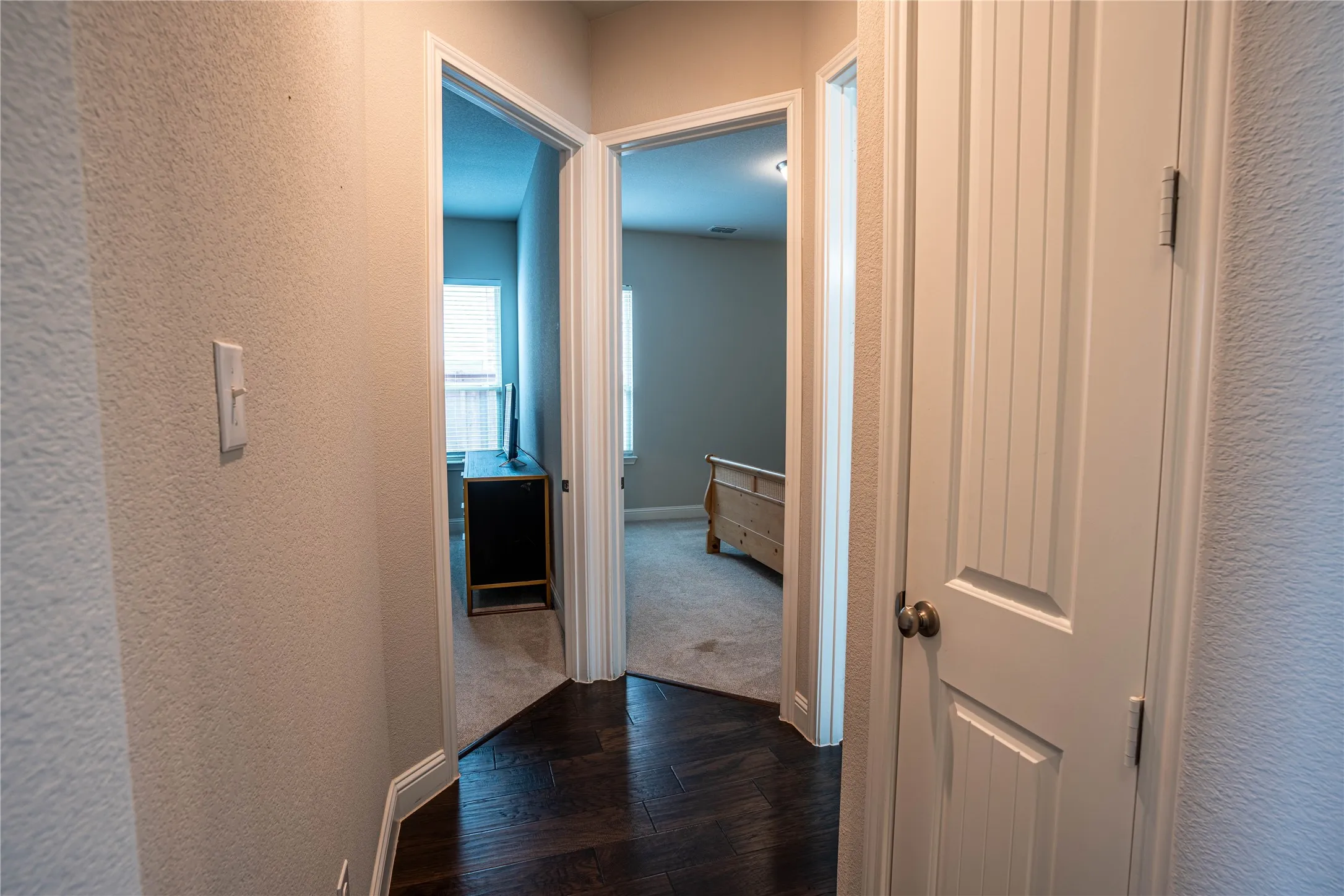 Hallway featuring rich dark wood-finish flooring, light neutral-toned walls, and white trim