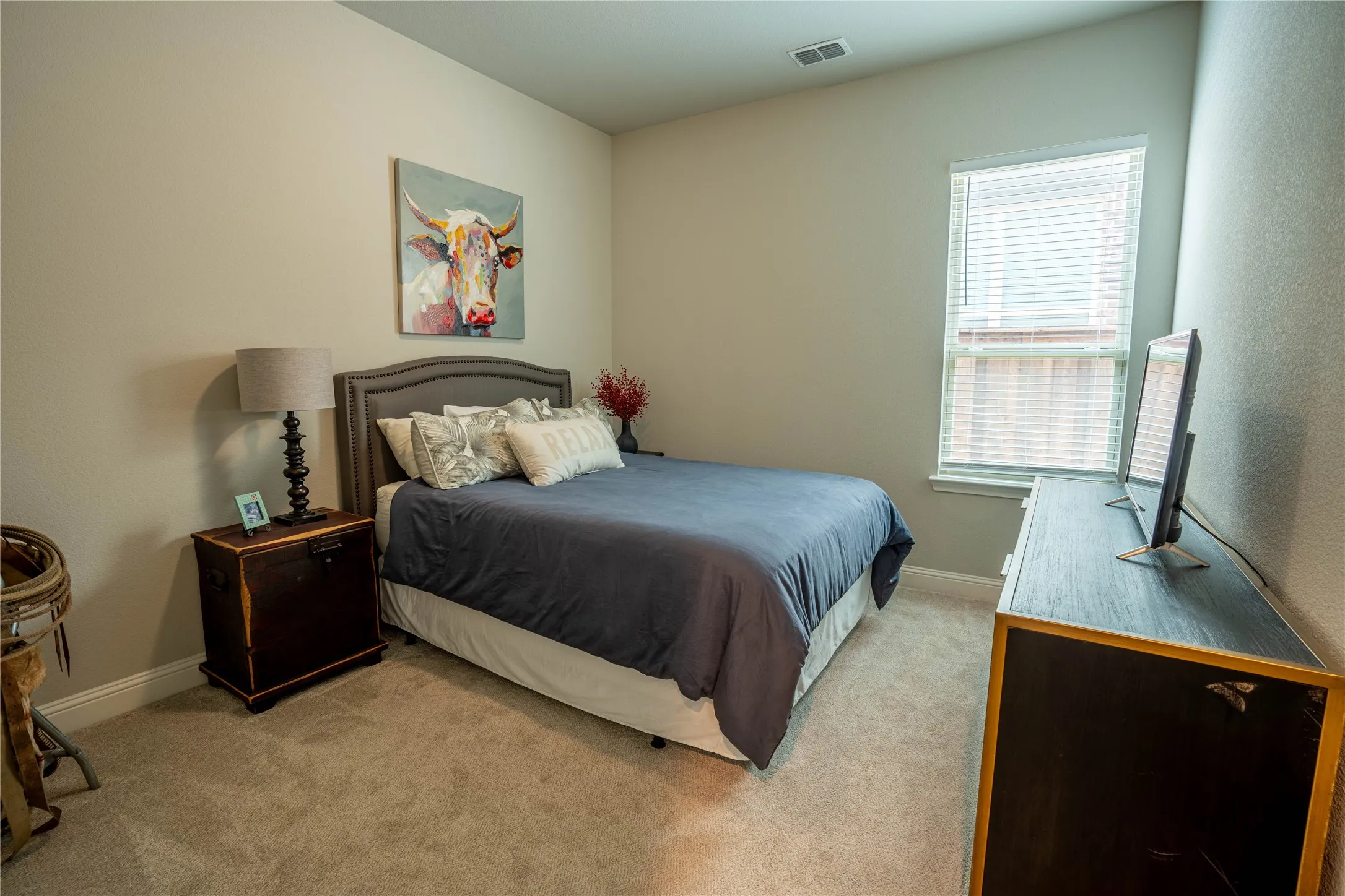 Carpeted room featuring a window with blinds, a built-in air vent, and light-toned walls