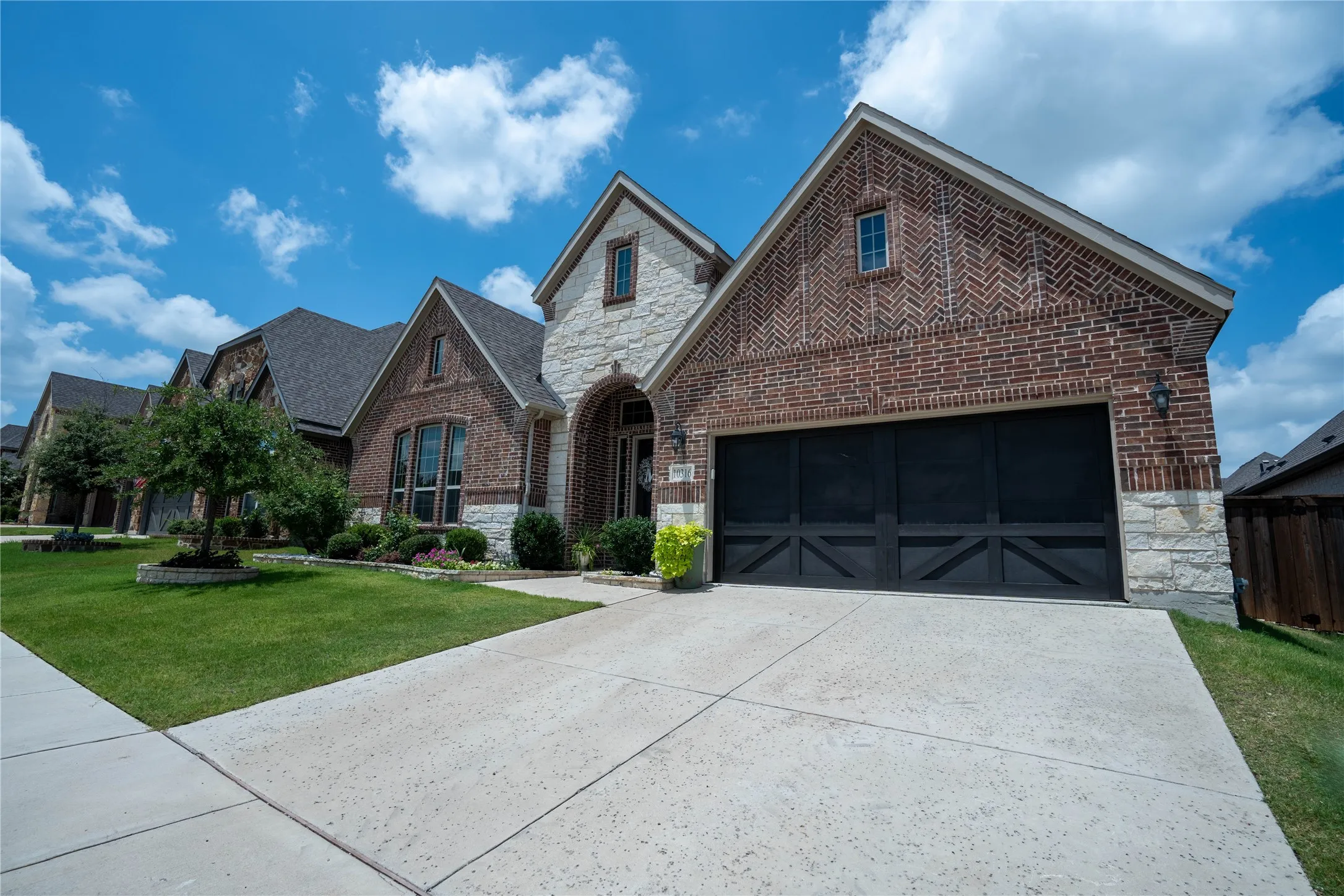 Brick and stone facade featuring a prominent two-car garage with black carriage-style doors