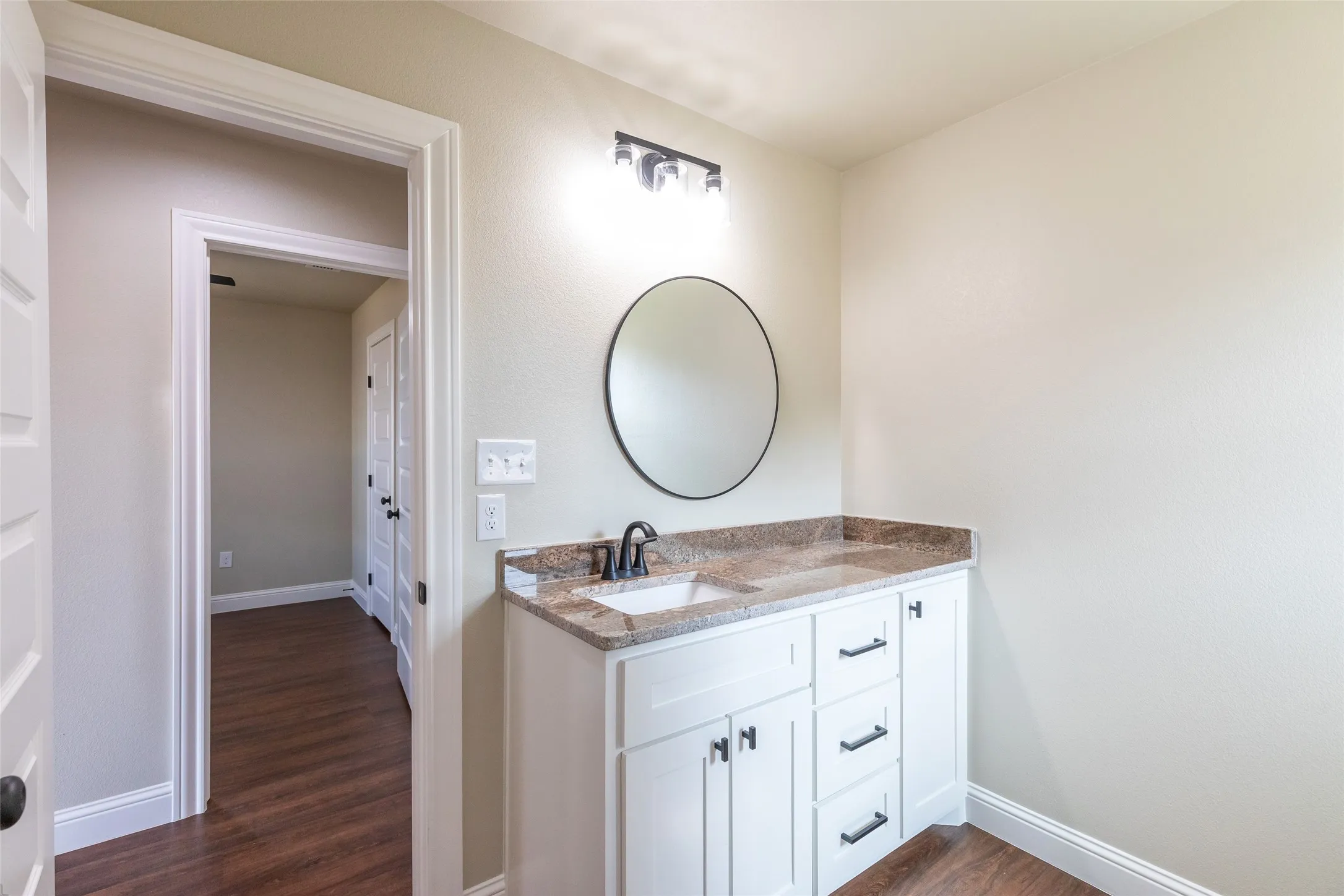 Bathroom vanity featuring a granite-style countertop, undermount sink, and black hardware
