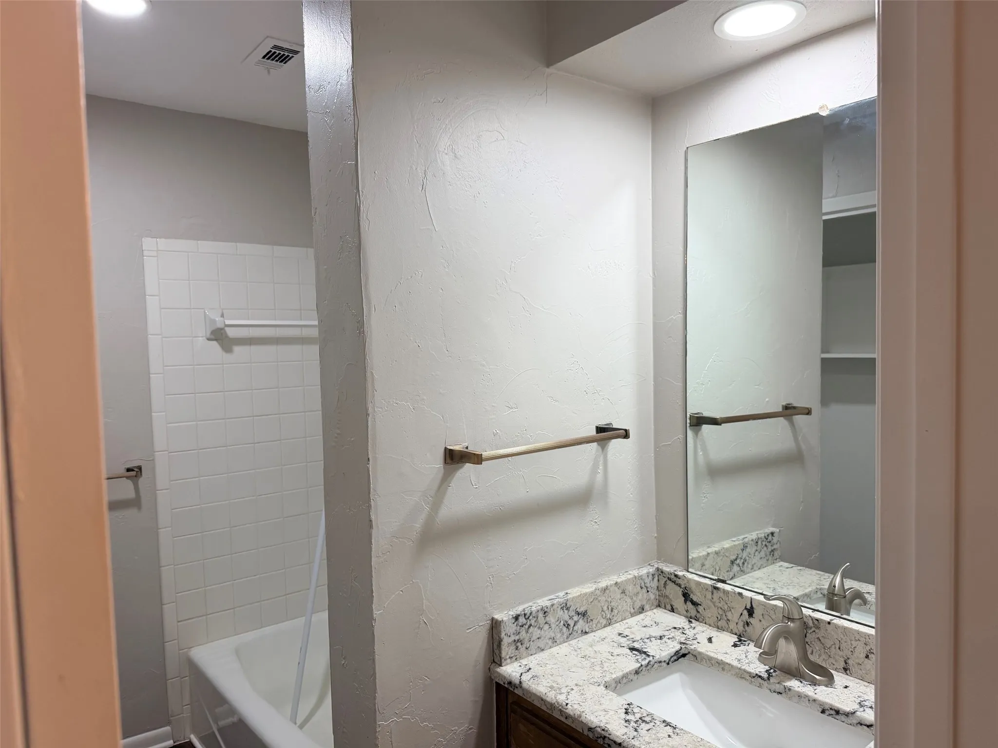Bathroom featuring a vanity with a white countertop and undermount sink, brushed nickel faucet, and a wall-mounted mirror