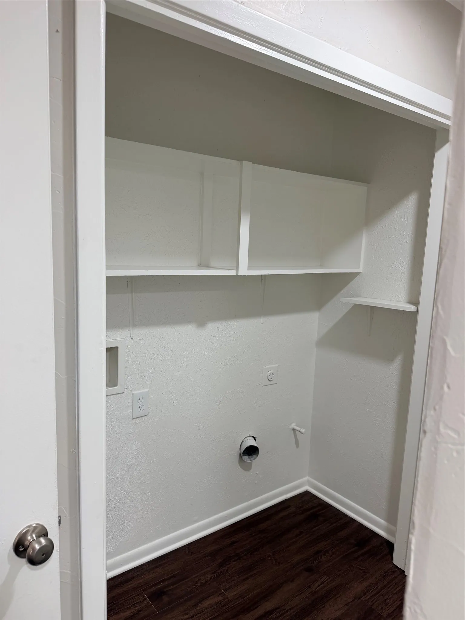 Dedicated utility closet featuring a dark wood-finish floor and white shelving