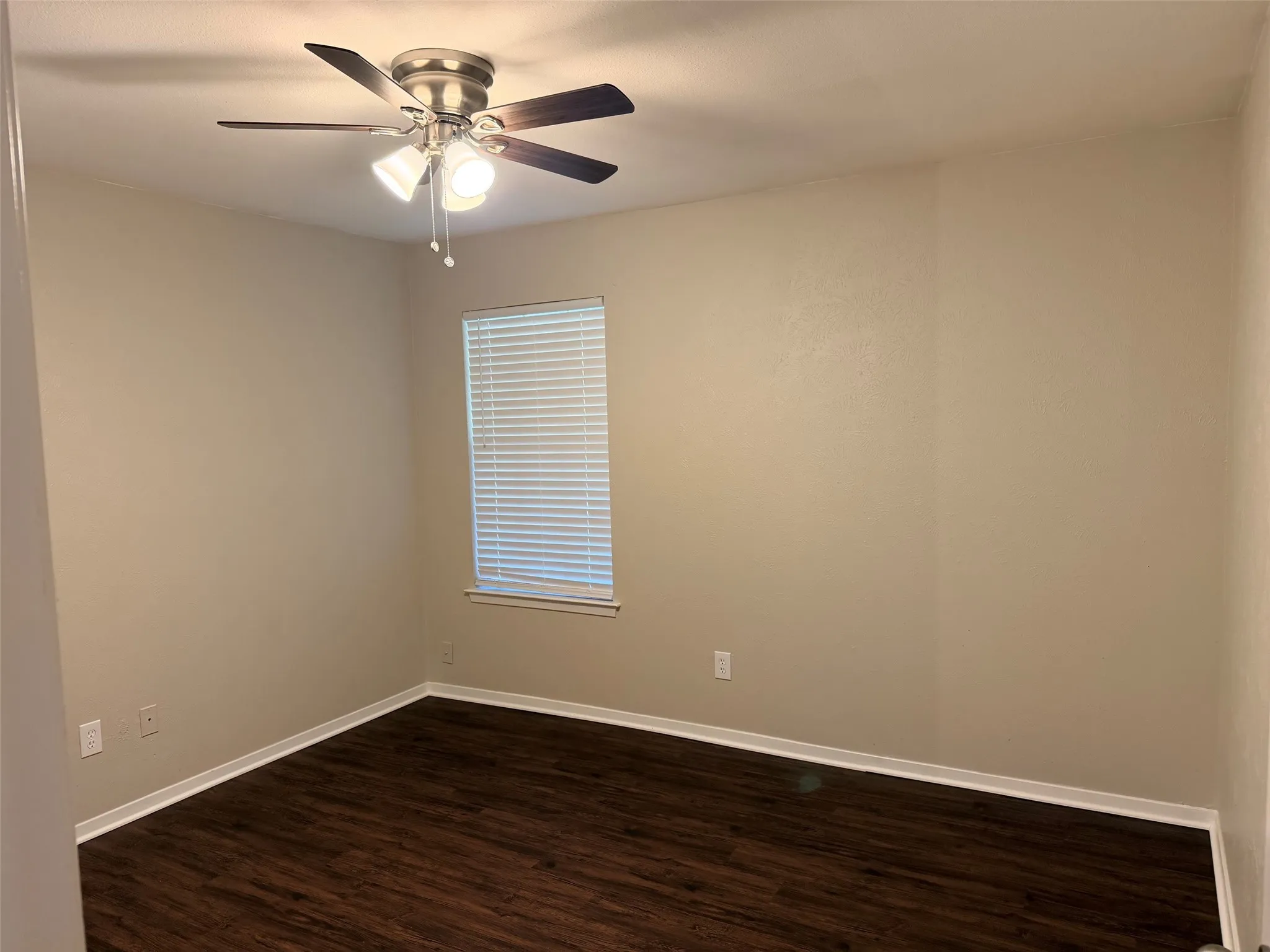 Room featuring wood-finish flooring, neutral wall tones, a ceiling fan with integrated lighting, and a window with horizontal blinds