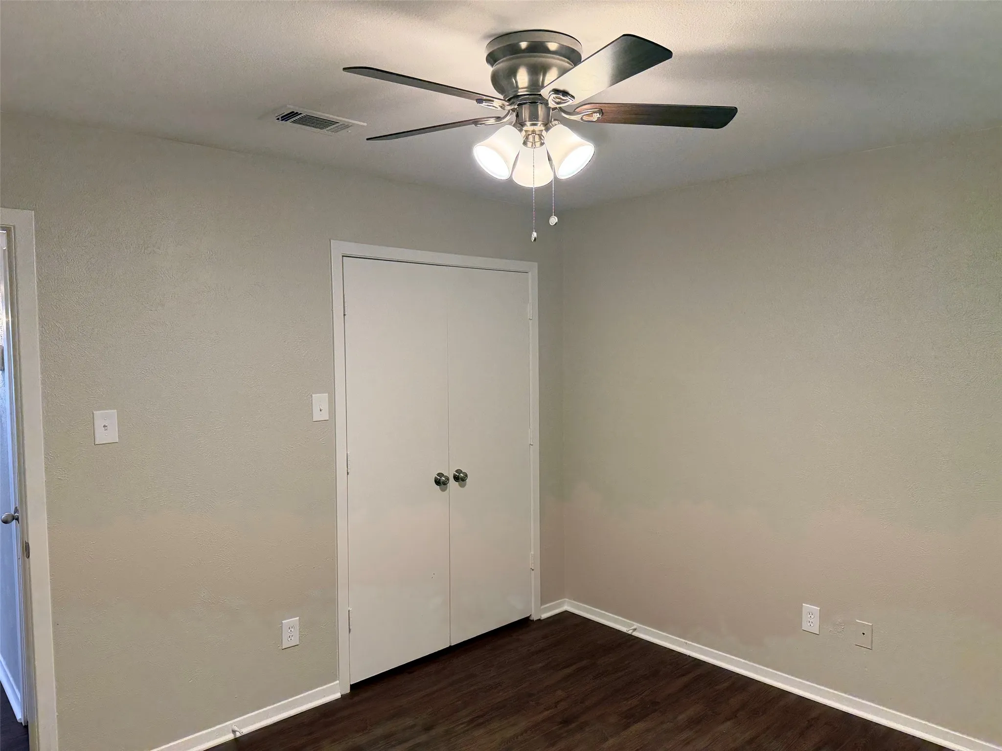 Room featuring wood-finish flooring, a ceiling fan with integrated lighting, and neutral wall paint