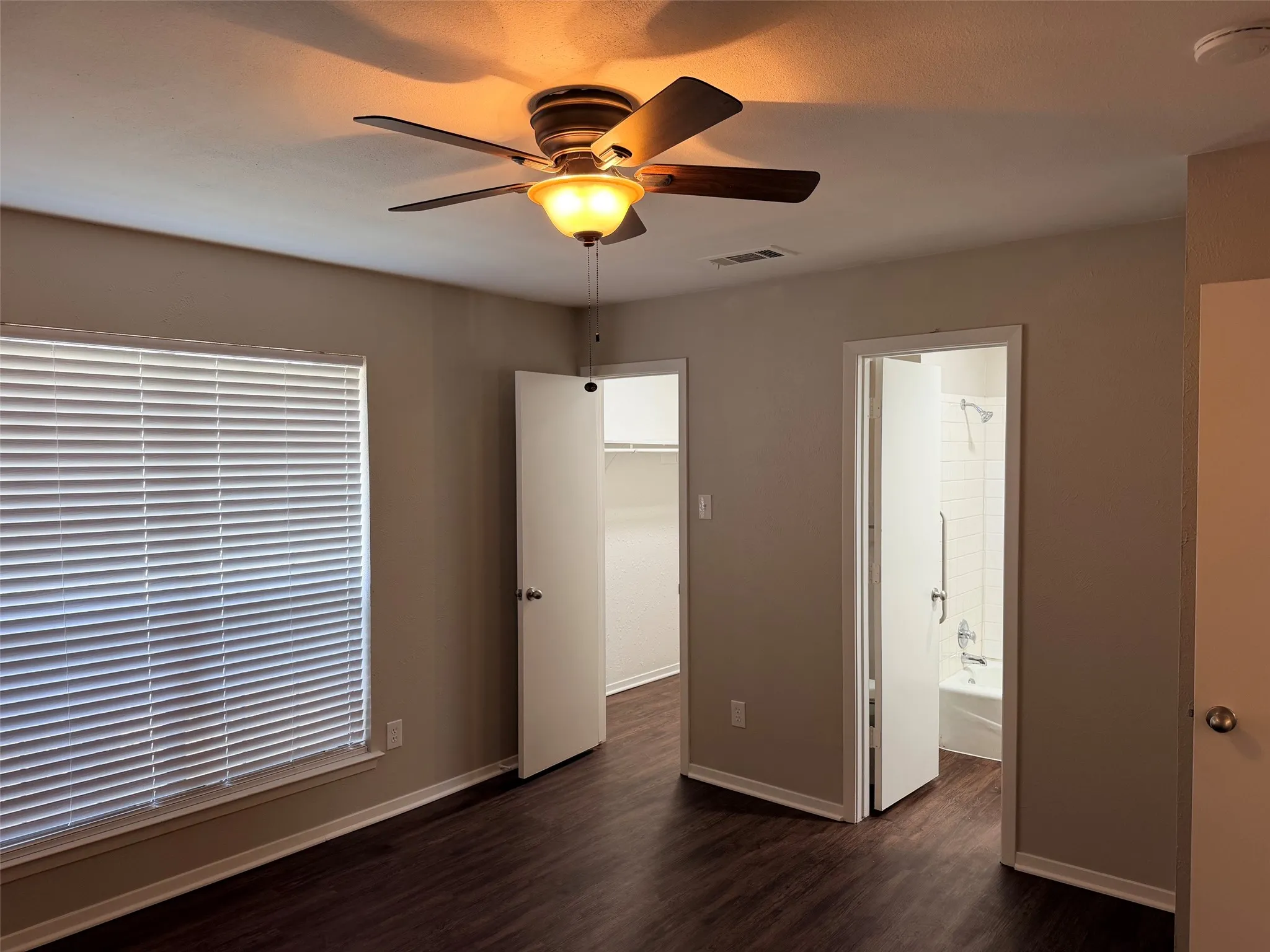 Bedroom featuring wood-finish flooring, a ceiling fan with integrated lighting, a window with blinds, and neutral wall paint