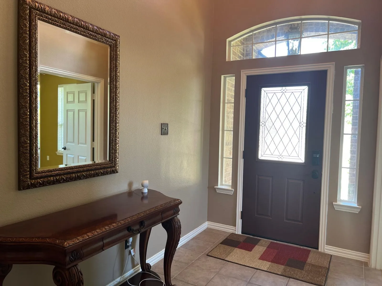 Entryway featuring a dark paneled door with leaded glass, side windows, and an arched transom window
