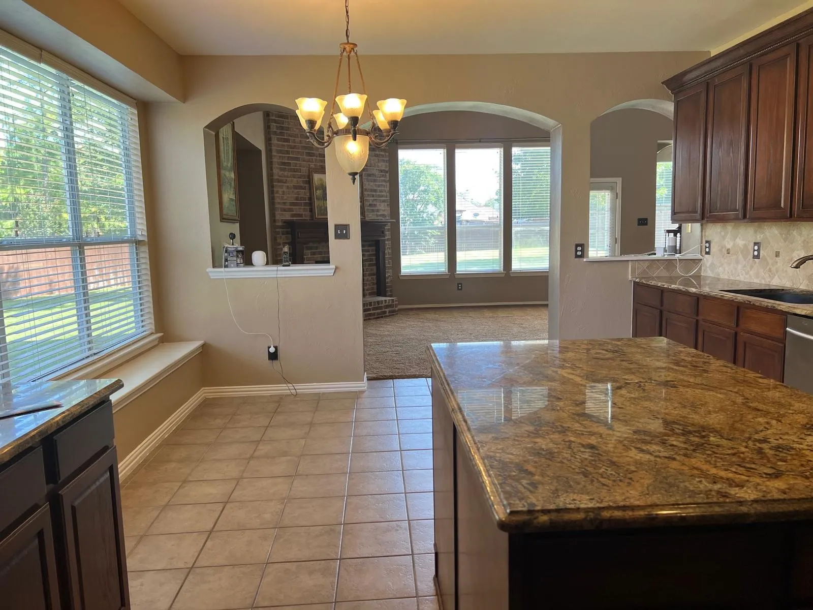 Kitchen featuring a large central island with a granite countertop, dark wood cabinetry, and stainless steel appliances