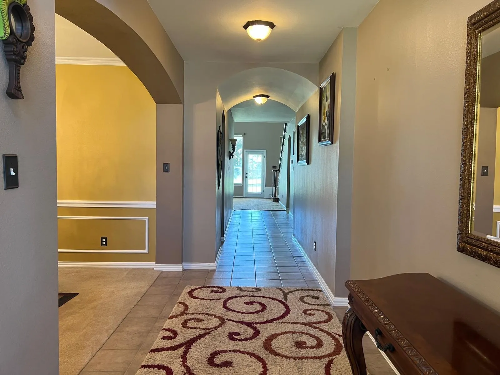Tiled entryway featuring an arched doorway, crown molding, and recessed lighting