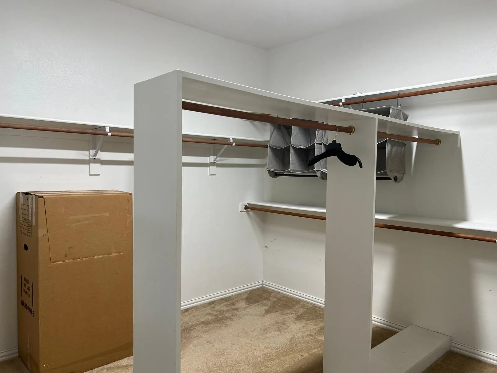 Walk-in closet with built-in shelving, multiple hanging rods, and carpet flooring
