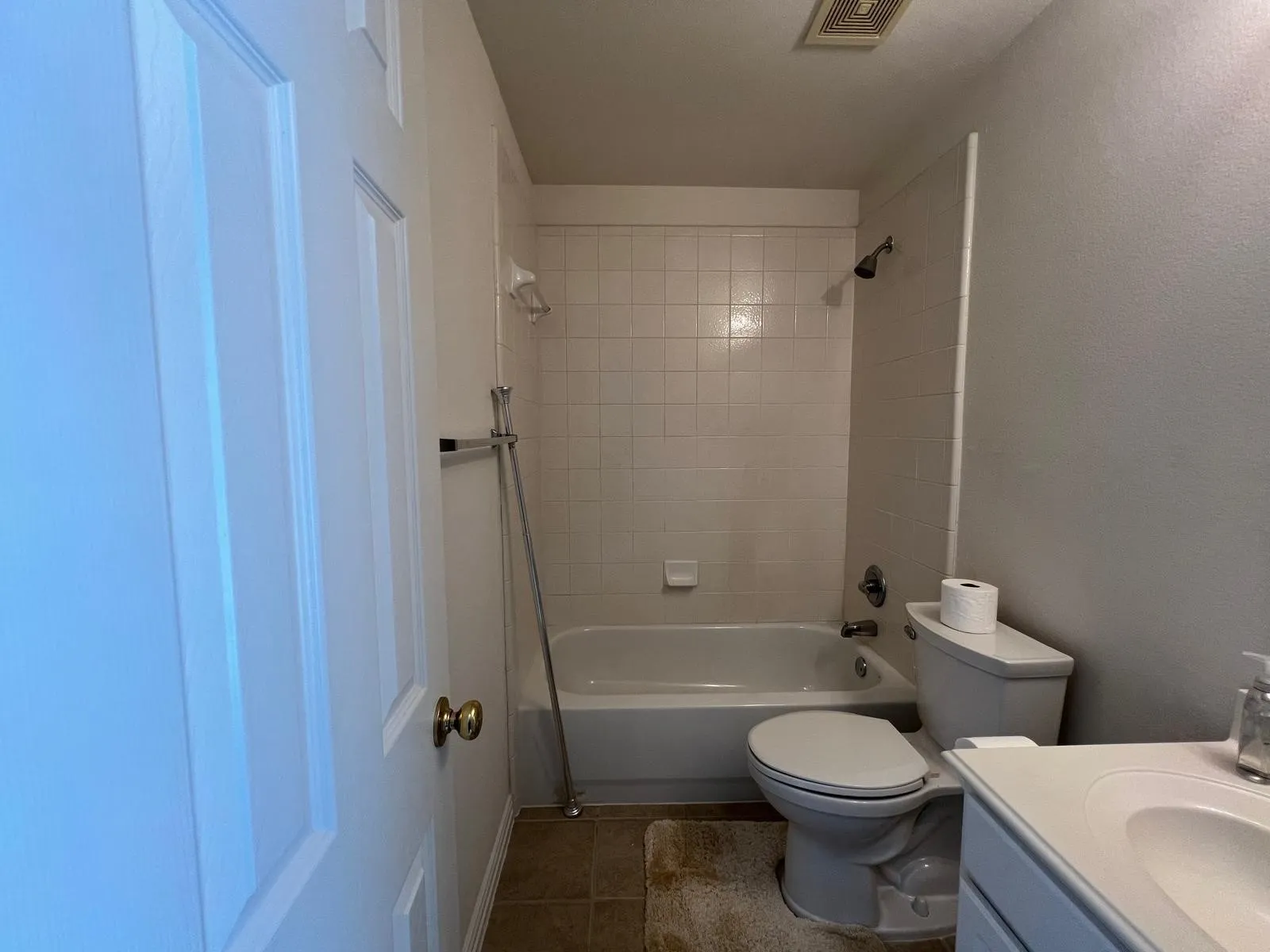 Bathroom featuring a tub/shower combination with white tile surround, a white toilet, and a vanity with an integrated sink