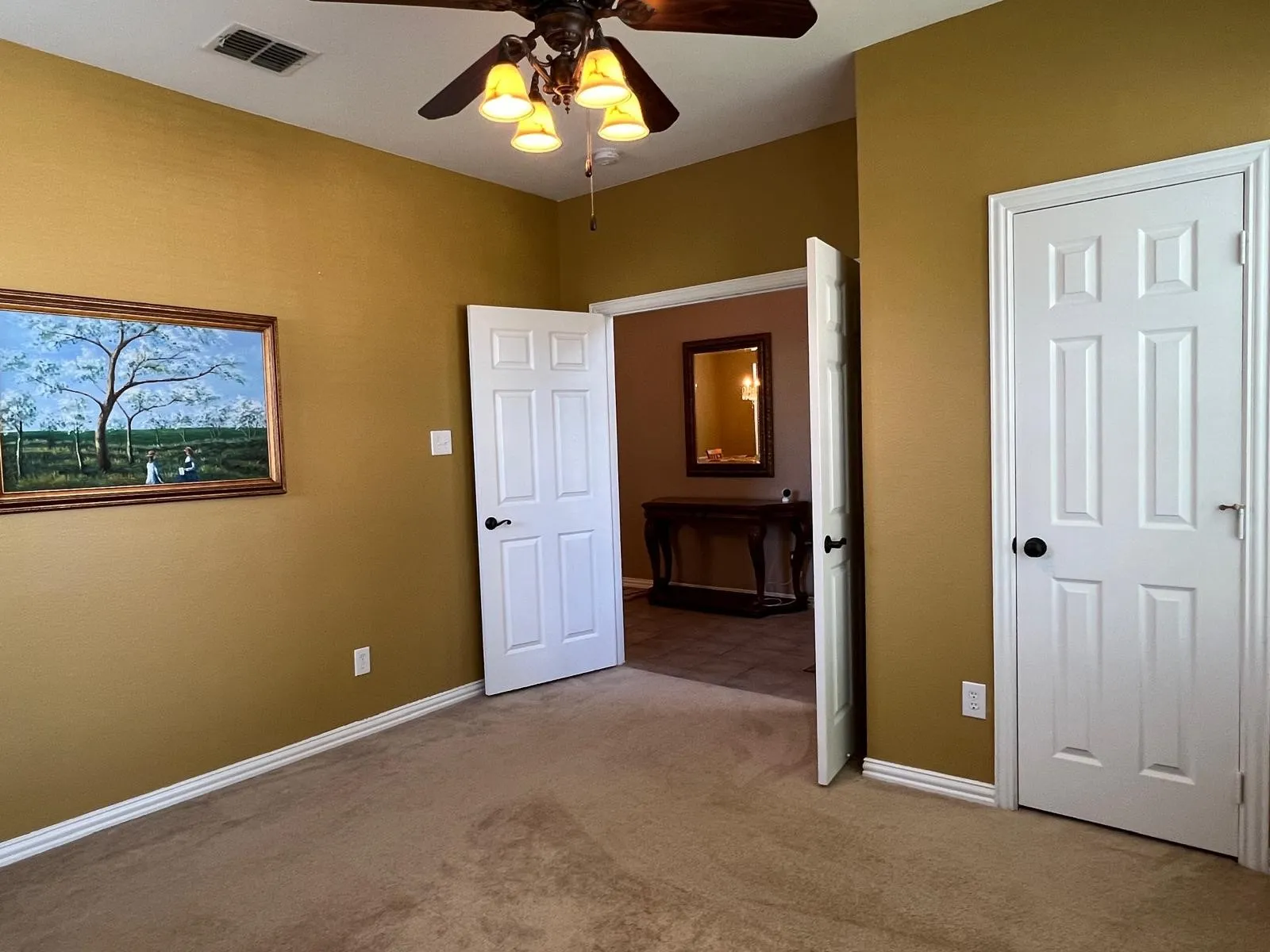 Carpeted room with warm-toned walls, white trim, and a ceiling fan with integrated lighting