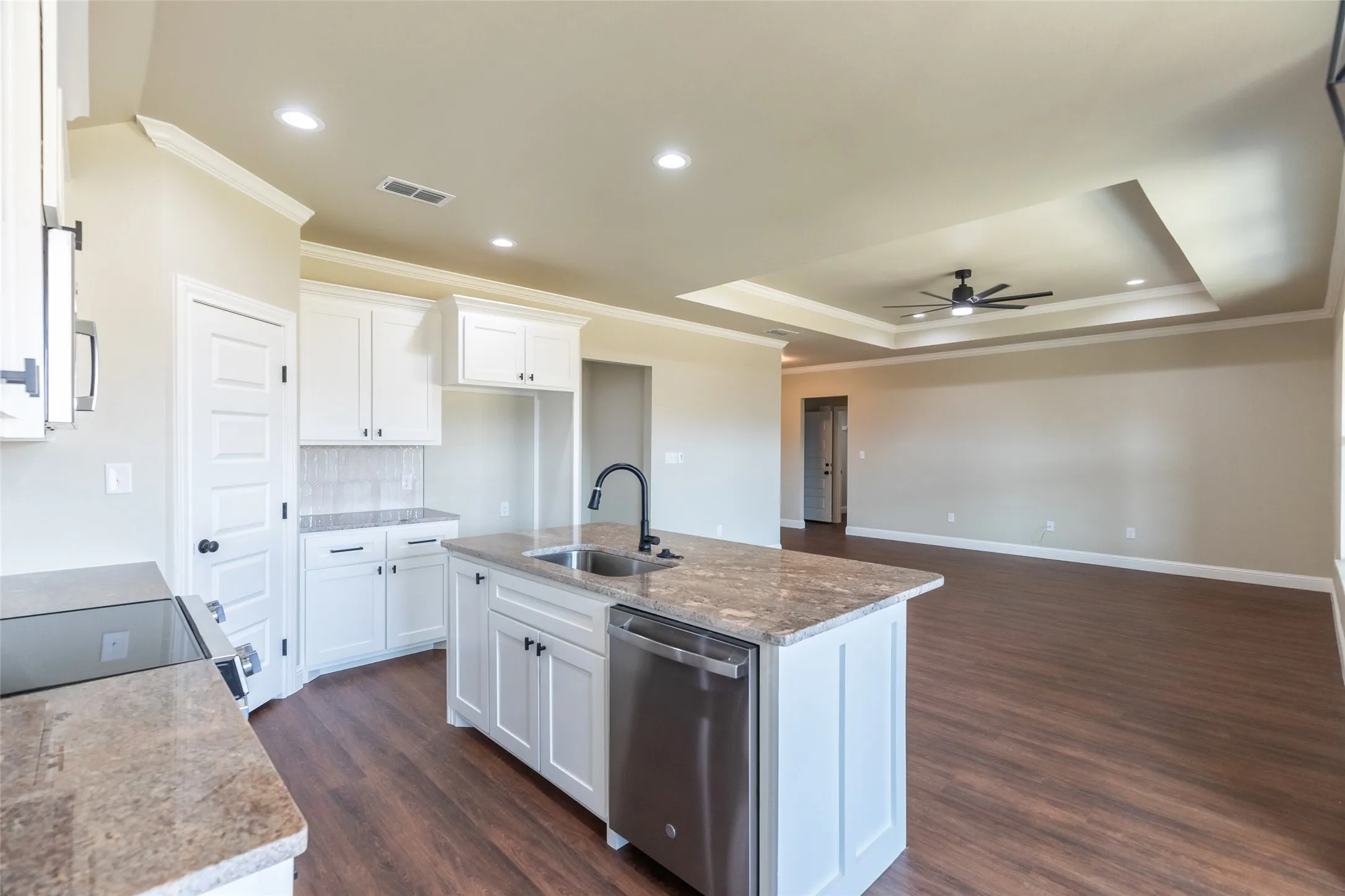 Kitchen island featuring an undermount sink with a gooseneck faucet and a built-in dishwasher
