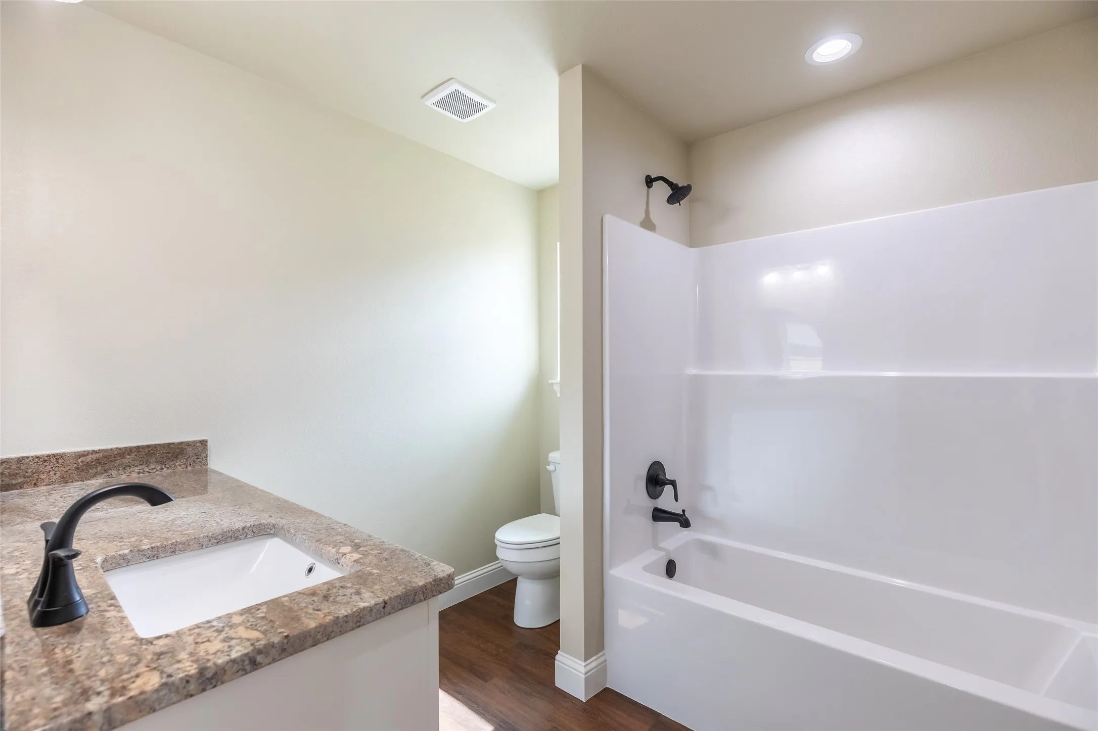 Bathroom featuring a vanity with an integrated sink, granite-style countertop, and dark-finish faucet