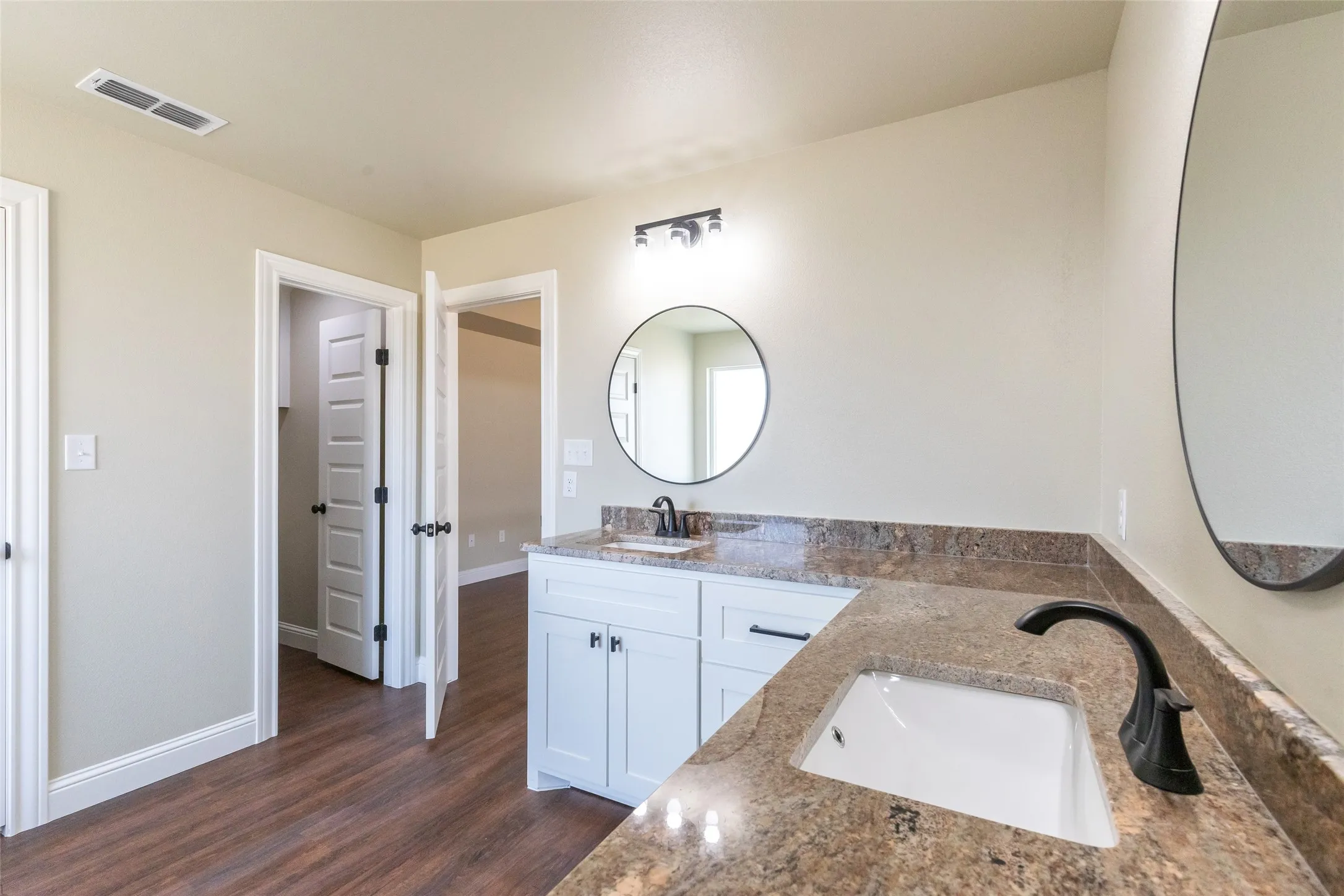 Double vanity featuring granite countertops, undermount sinks, and matte black fixtures