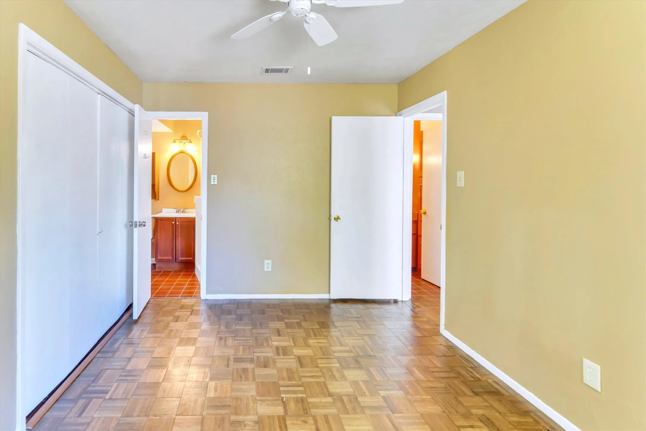 Parquet wood-finish flooring, ceiling fan, and light-toned walls
