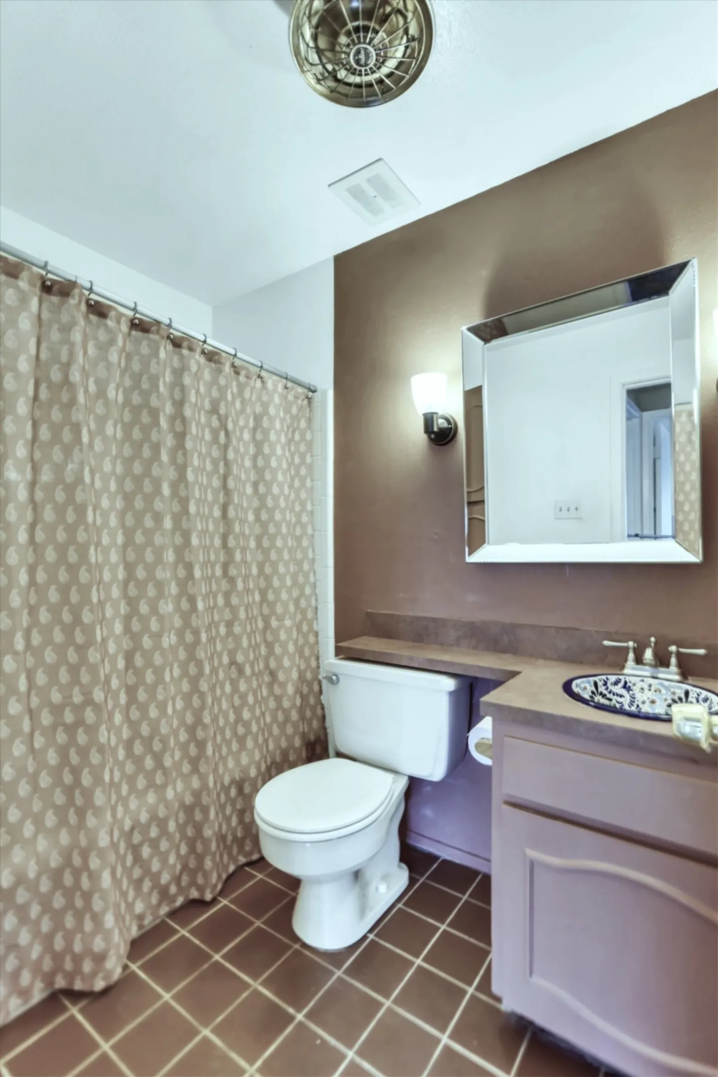 Bathroom featuring a vanity with a counter-mounted sink, a wall-mounted mirror, and tile flooring