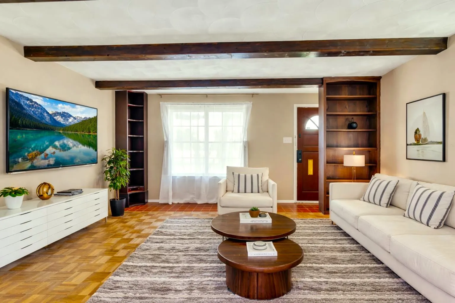 Living area featuring exposed wood beams, built-in shelving, wood-finish flooring, and a window with natural light
