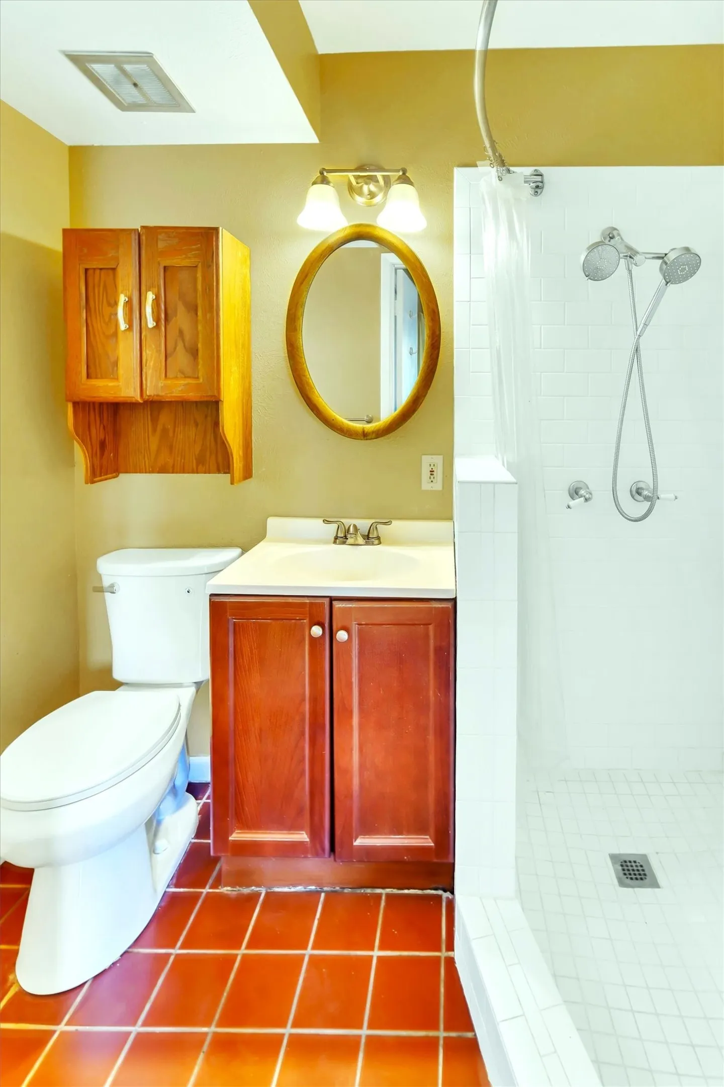 Bathroom featuring a shower with white subway tile, a dual-head shower fixture, and a curved shower rod