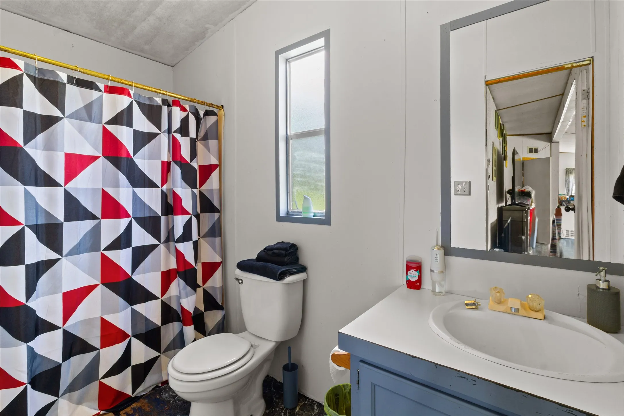 Bathroom featuring a single basin vanity with a white countertop, a mirror with a gray frame, and a white toilet