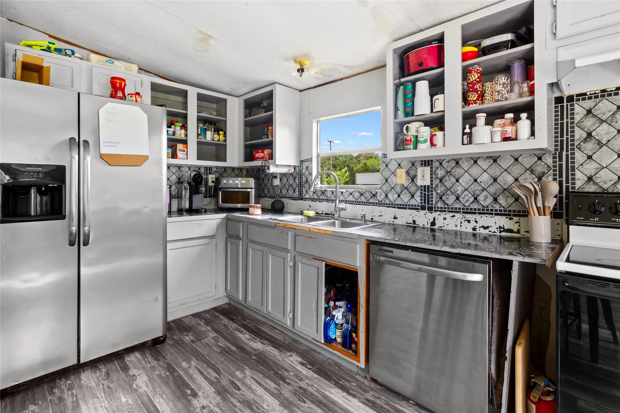 Kitchen featuring wood-finish flooring, light-colored cabinetry, a stainless steel refrigerator, and a stainless steel dishwasher