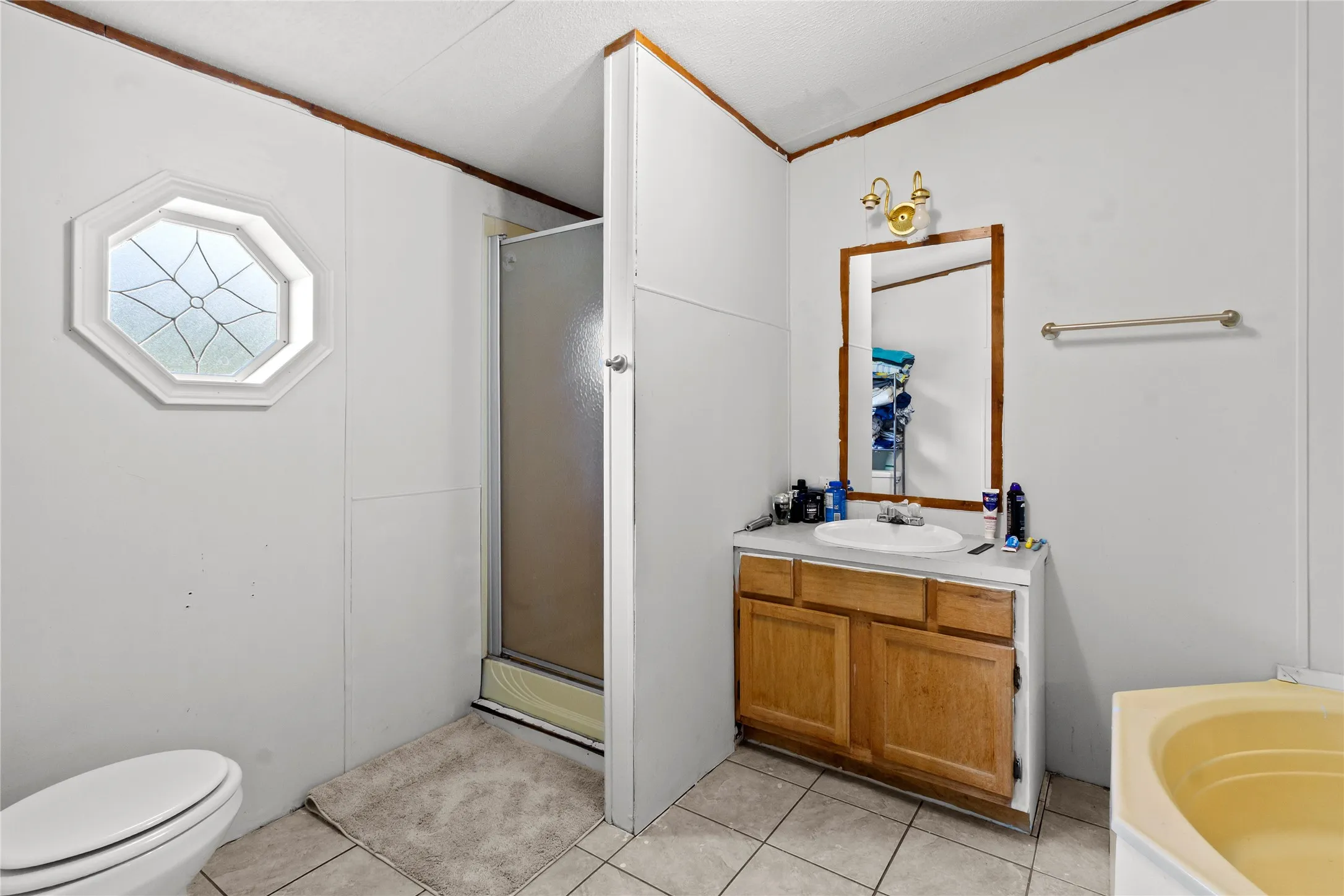 Bathroom featuring a vanity with a wood-finish cabinet, a full mirror, and an octagonal decorative window