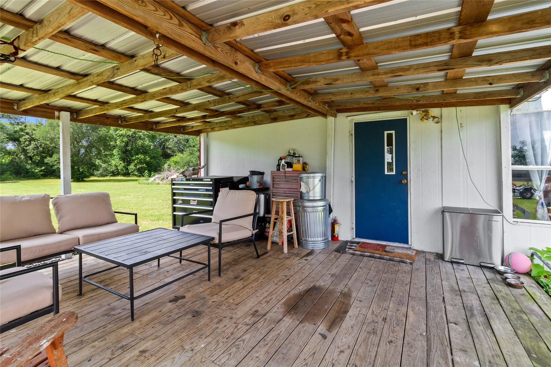 Expansive covered porch featuring wood-finish flooring and a metal roof supported by exposed wood beams