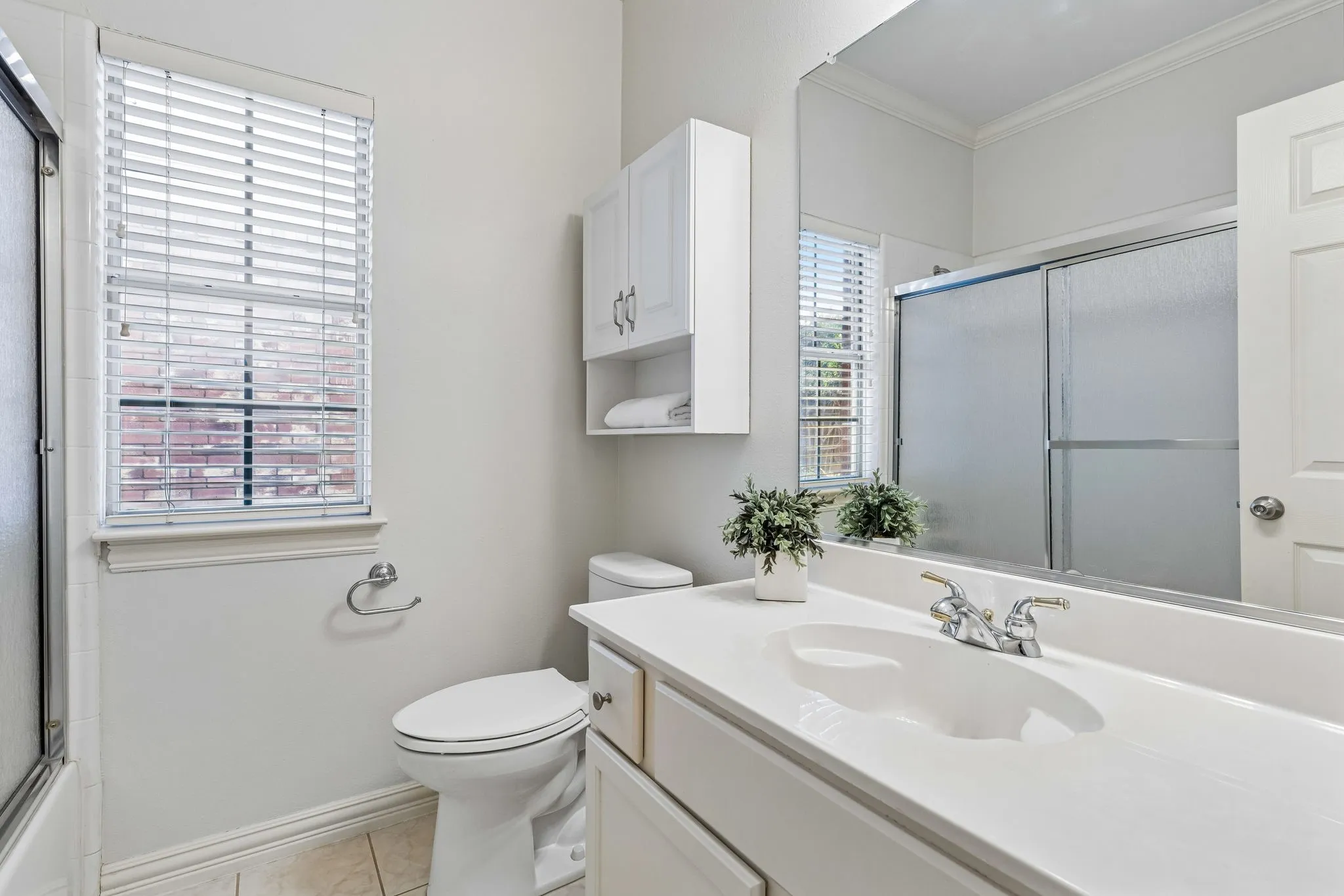 Bathroom featuring a white vanity with integrated sink, a large wall-mounted mirror, and a shower with sliding glass doors