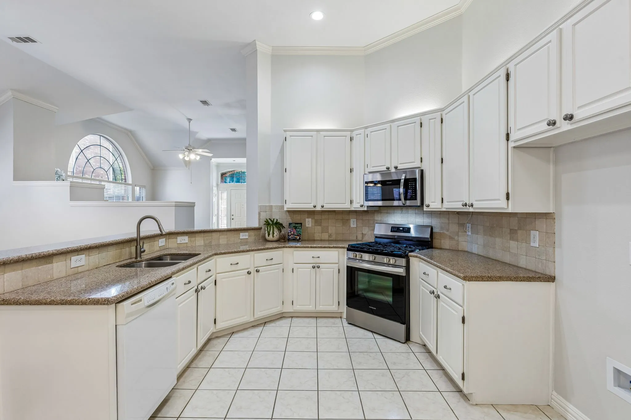 Kitchen featuring white cabinetry, stainless steel appliances, granite-finish countertops, tiled backsplash, and ceramic tile flooring