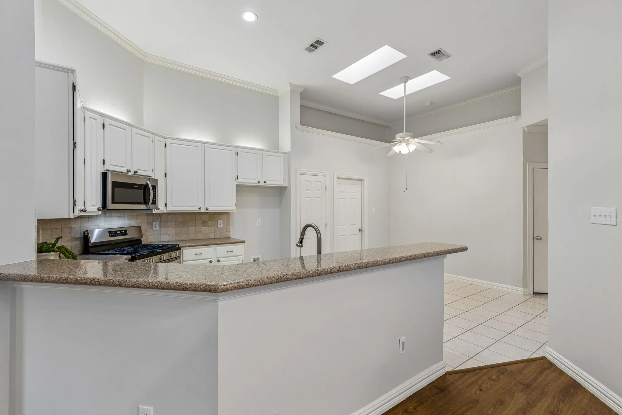 Kitchen featuring white cabinetry with stainless steel appliances, granite countertops, and a tiled backsplash