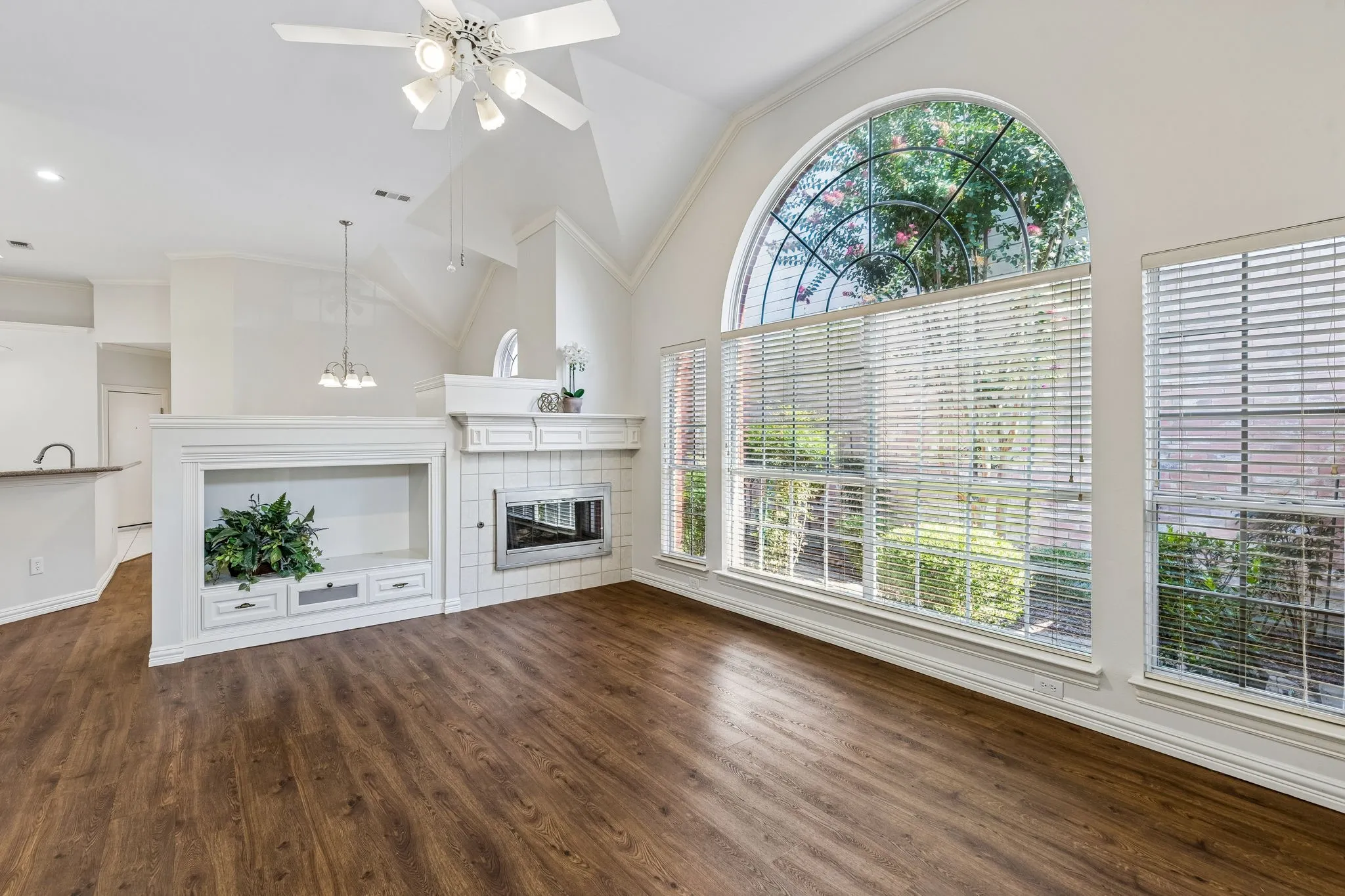 Spacious living area featuring wood-finish flooring and a vaulted ceiling with a white ceiling fan
