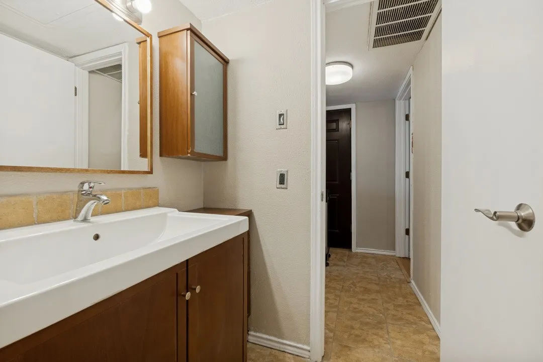 Bathroom vanity featuring a single basin sink, chrome faucet, and wood-finish cabinetry