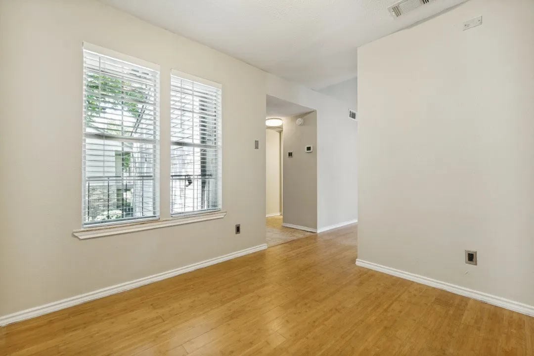 Two windows with white blinds, wood-finish flooring, white baseboards, and neutral wall paint