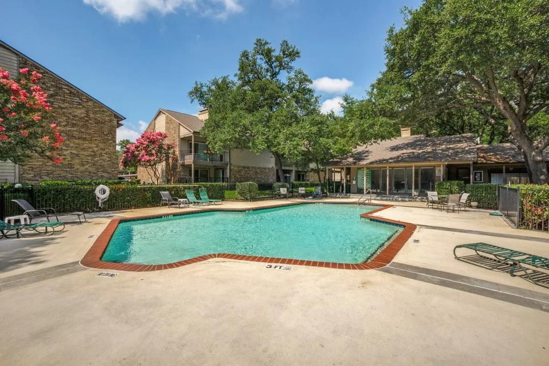 Outdoor swimming pool with a red brick coping and surrounding concrete decking